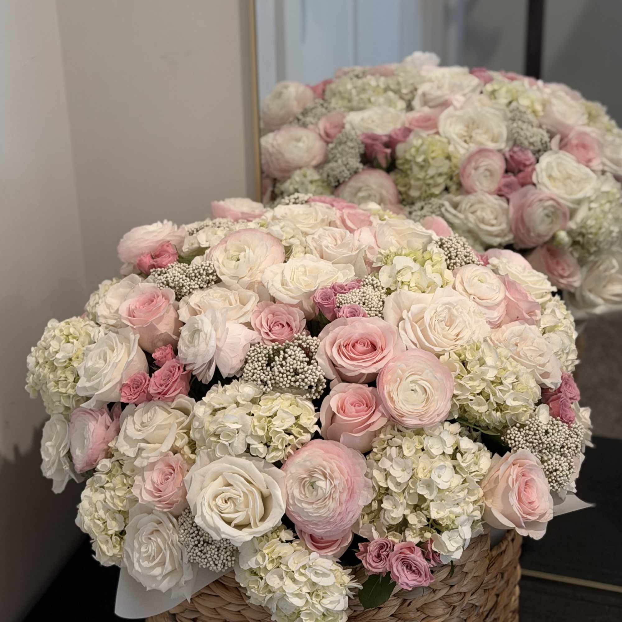 Large pink and white rose arrangement in a woven basket