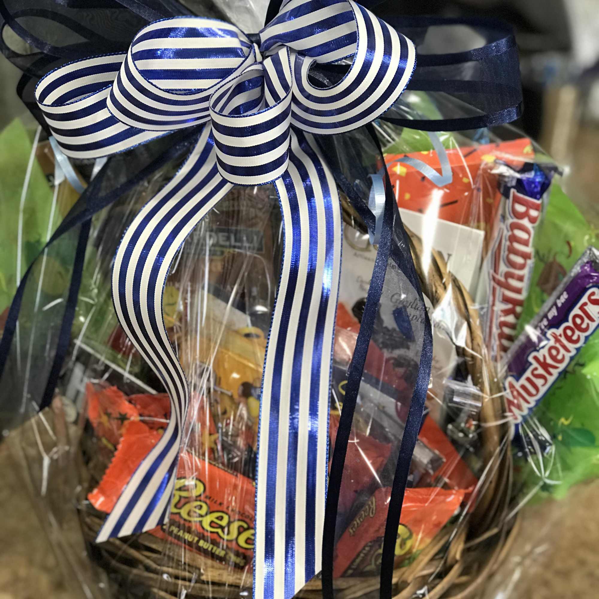 Gift basket wrapped in clear cellophane with a blue striped bow