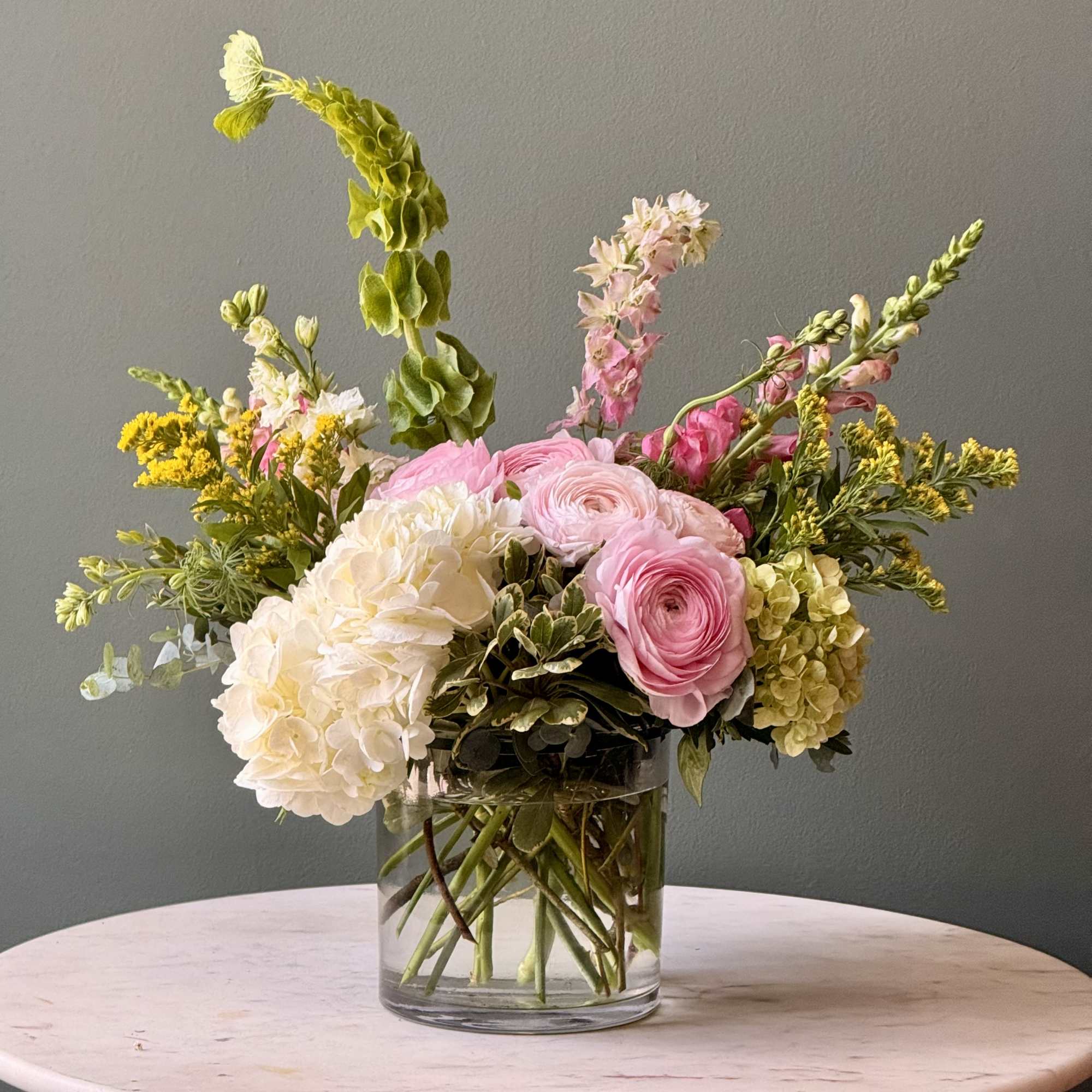 Pink and white flowers arranged in a clear glass vase