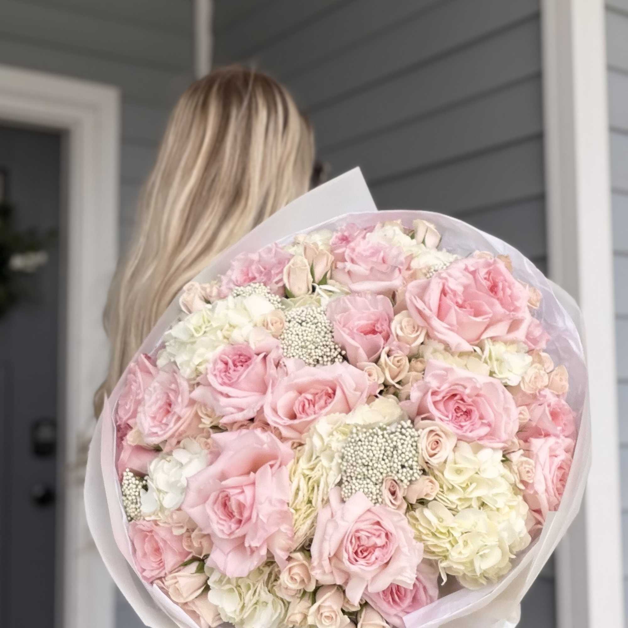 Large bouquet of pink and white roses wrapped in pale paper