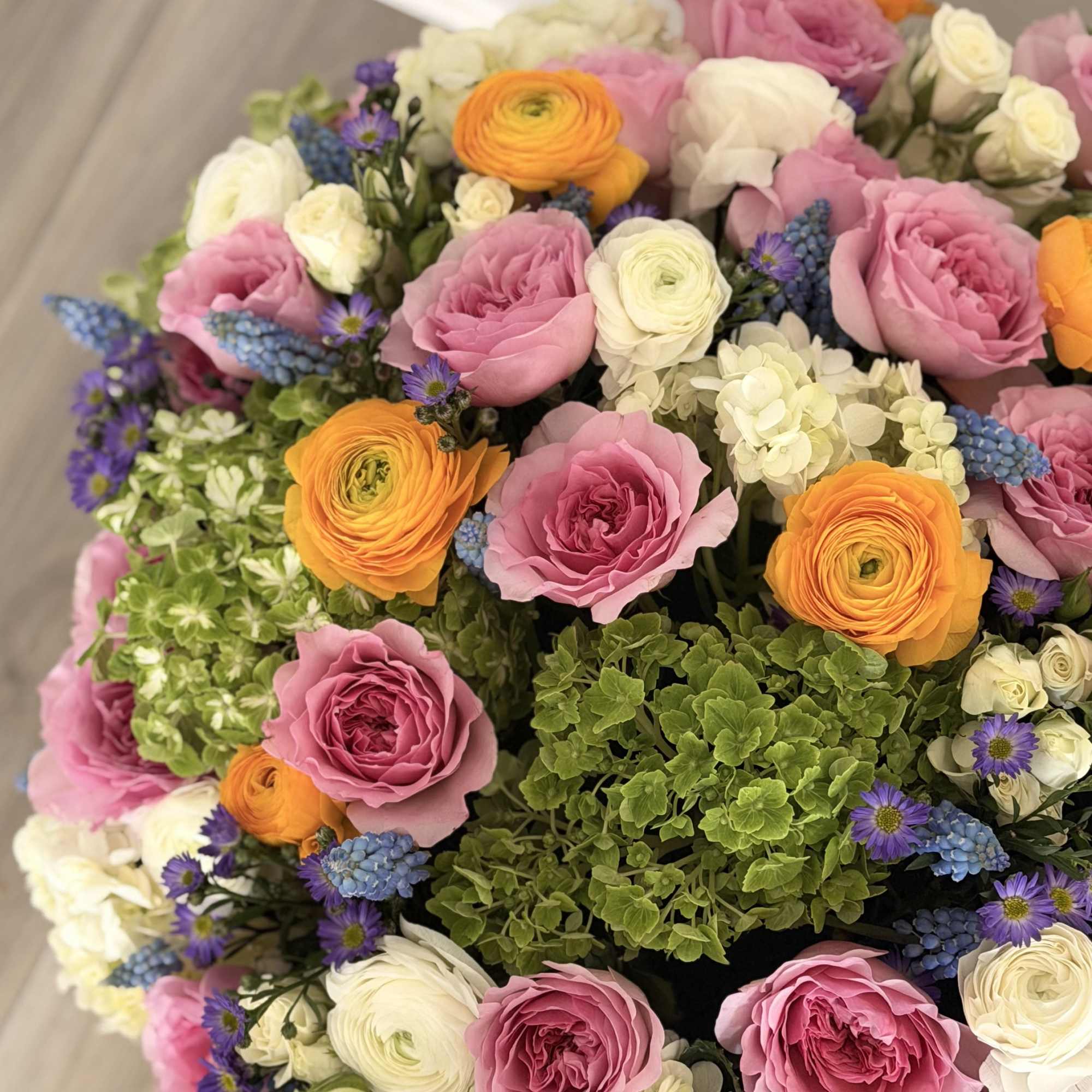 Round bouquet of pink, white, orange, and blue flowers