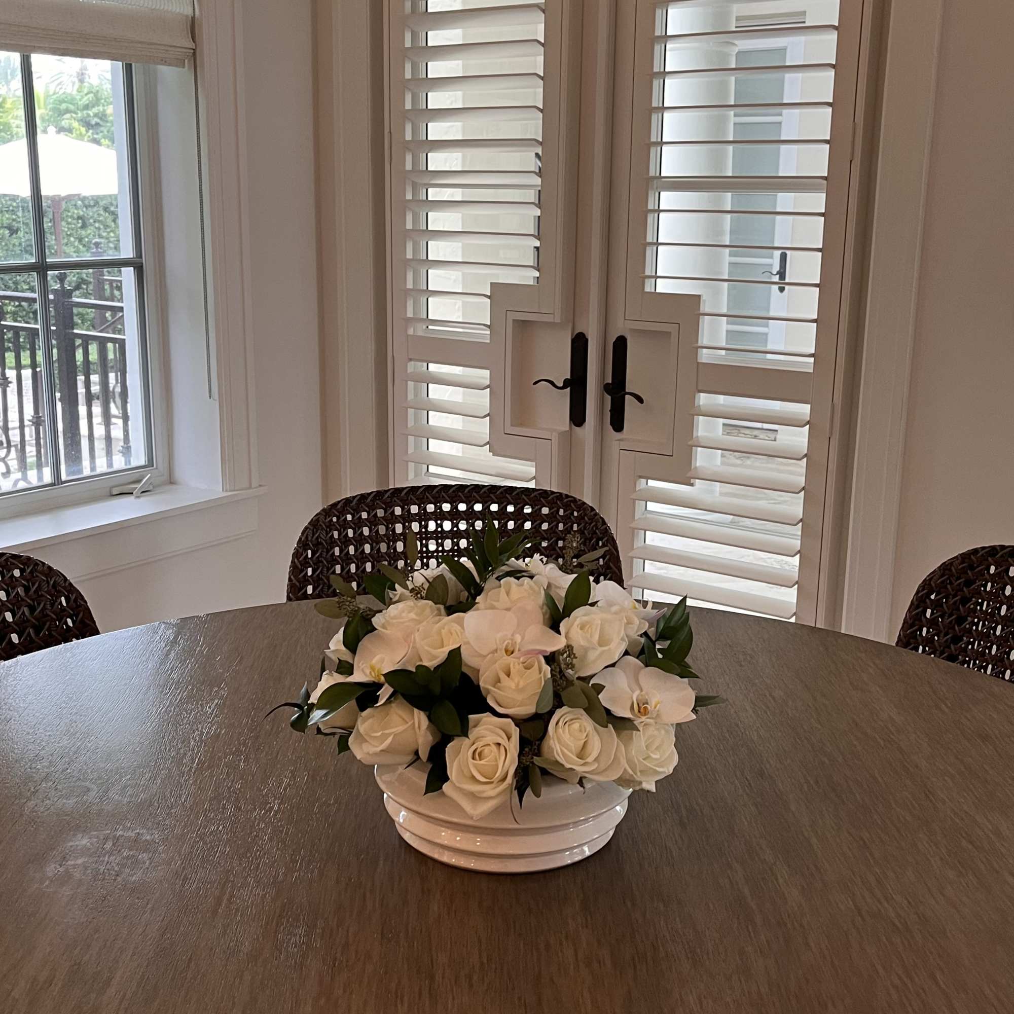 White rose and orchid arrangement in a low white bowl on a table