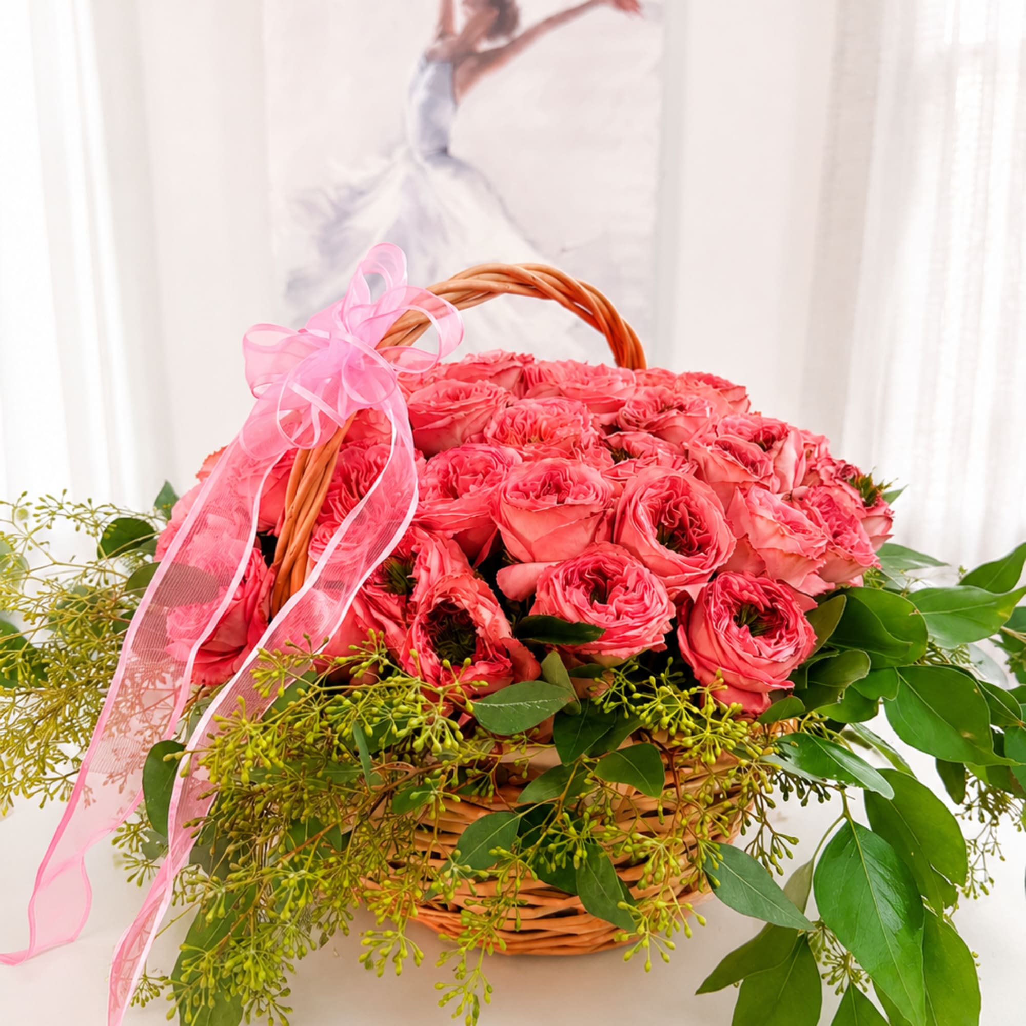Pink roses in a wicker basket with a pink ribbon