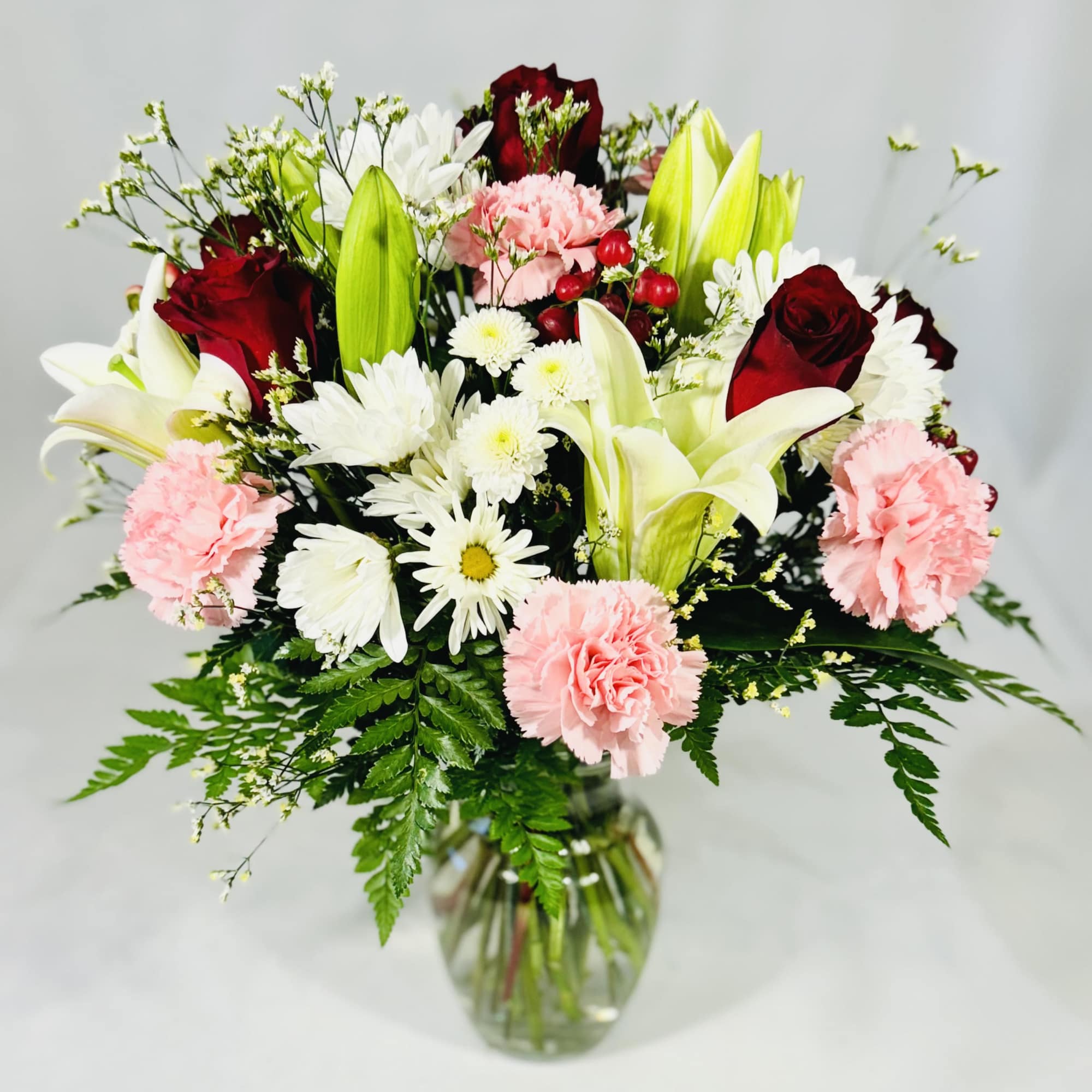 Bouquet of lilies, roses, carnations, and daisies in a glass vase