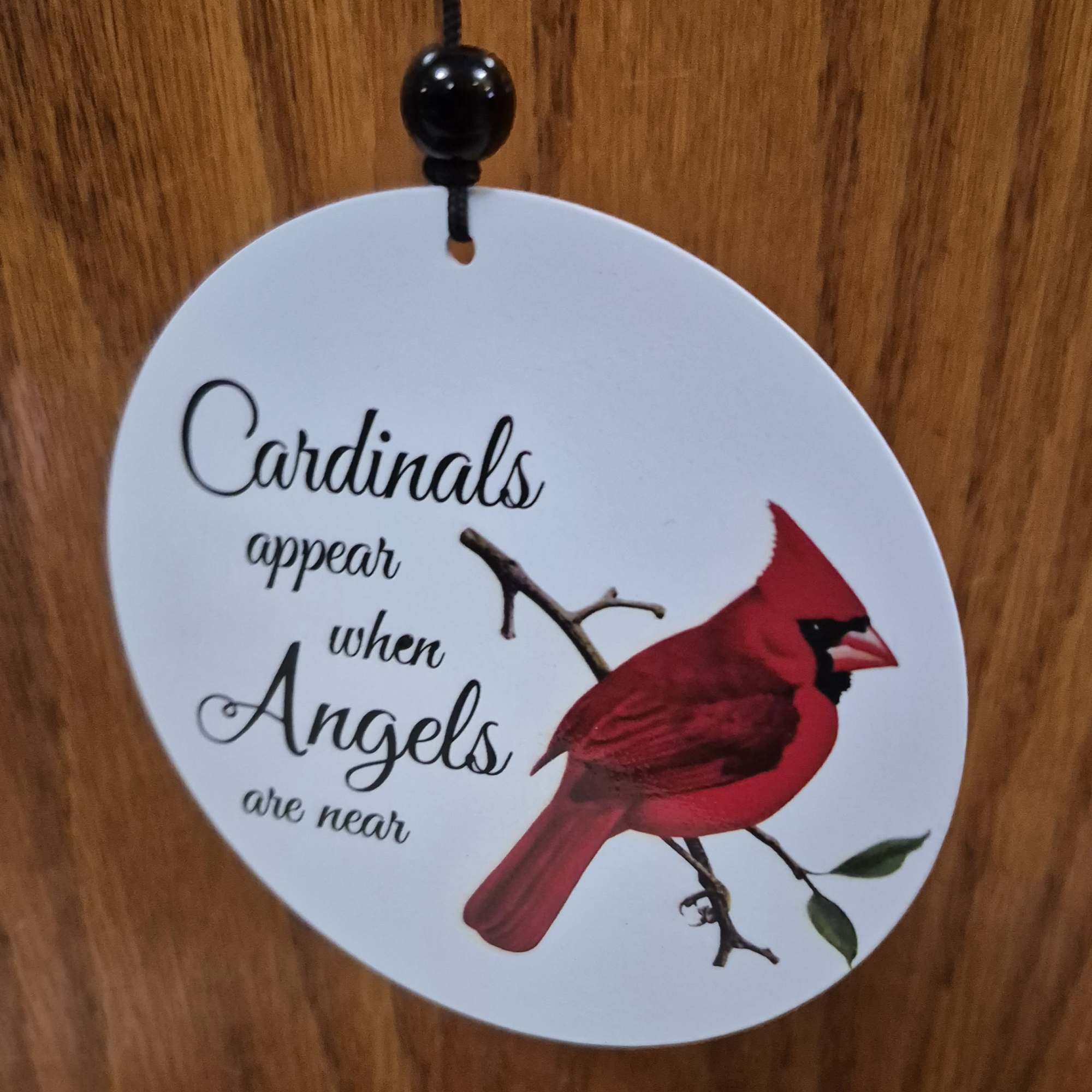 A tall, reflective wind chime emblazoned with vivid red cardinals offers a