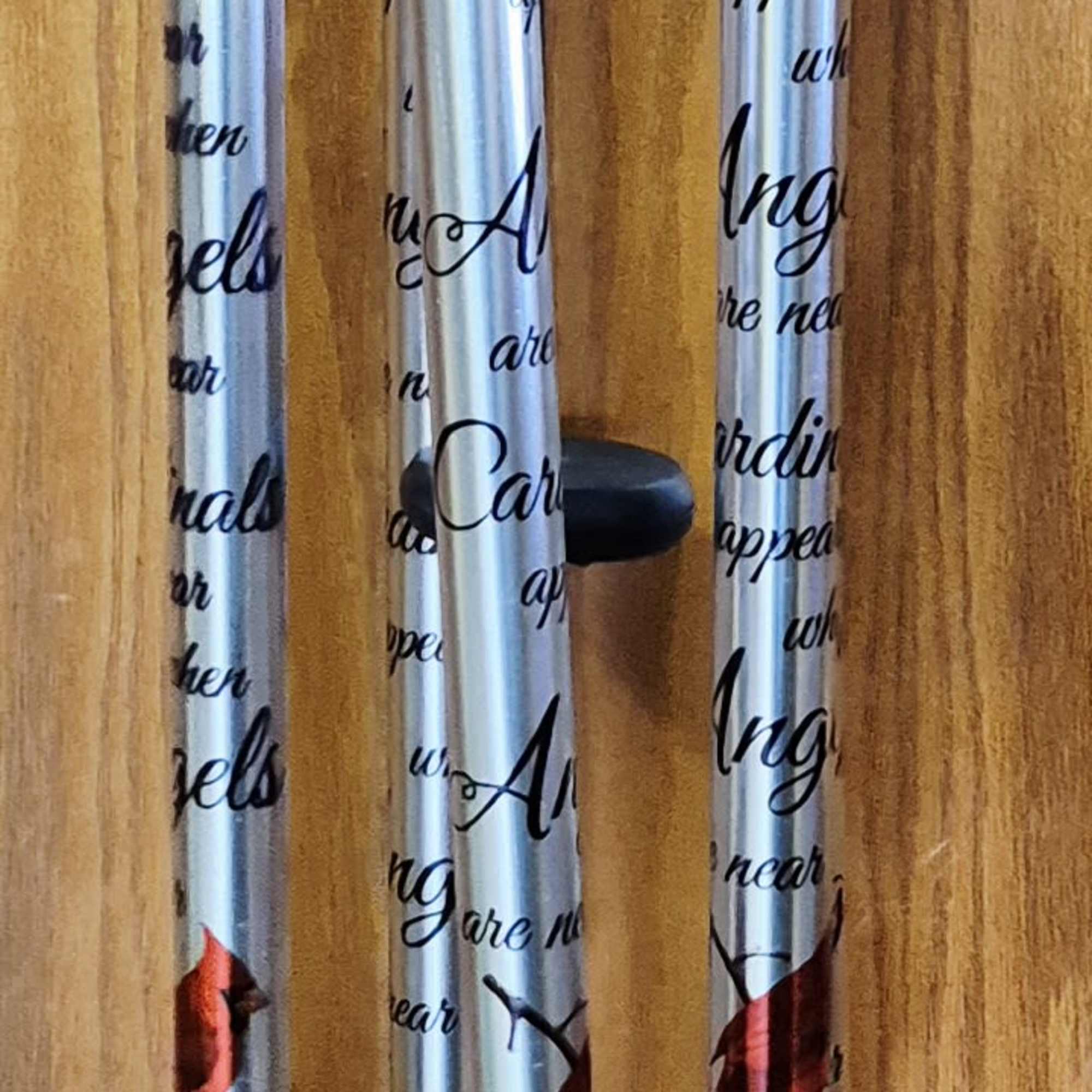 A tall, reflective wind chime emblazoned with vivid red cardinals offers a