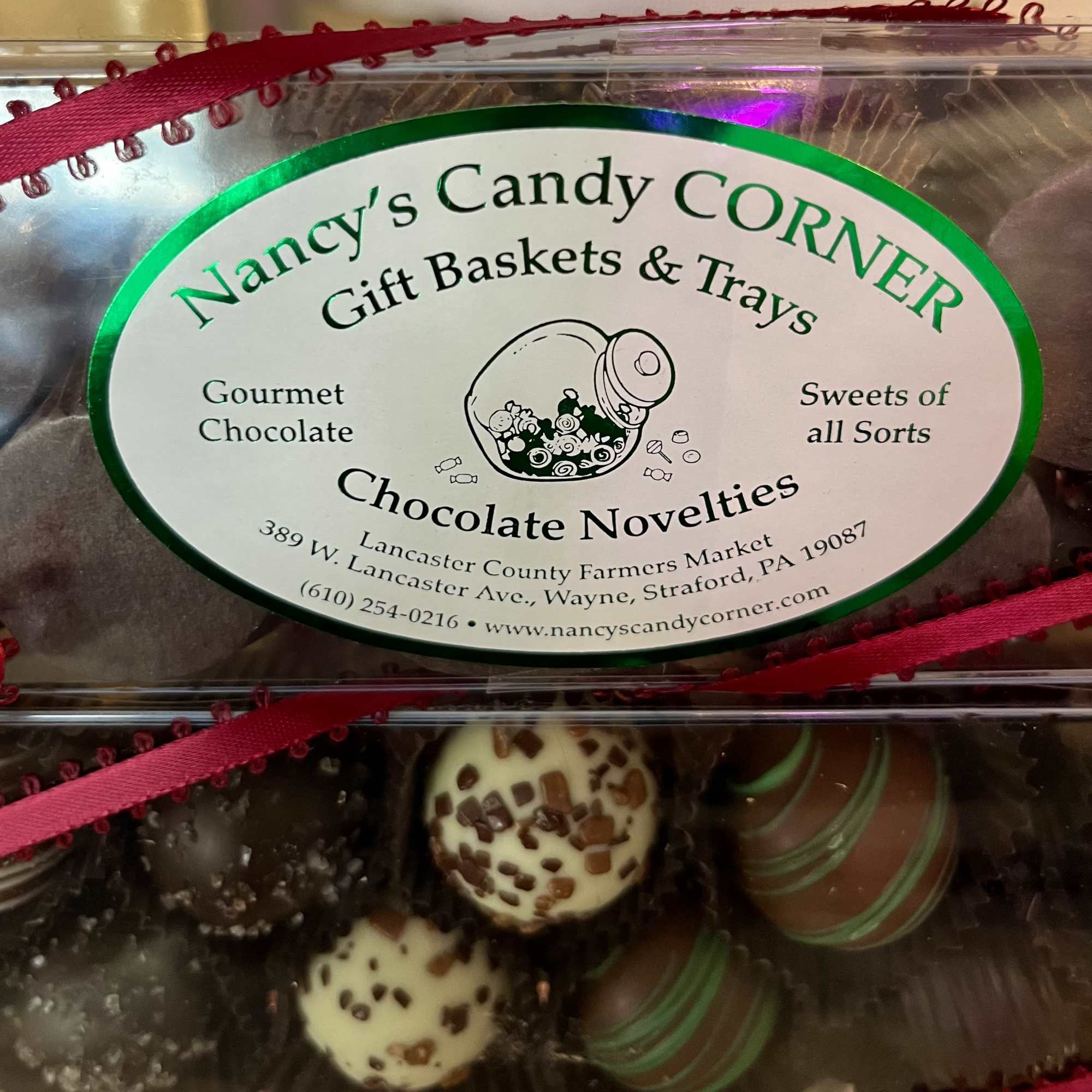 Box of assorted chocolate truffles with Nancy's Candy Corner label and red ribbon