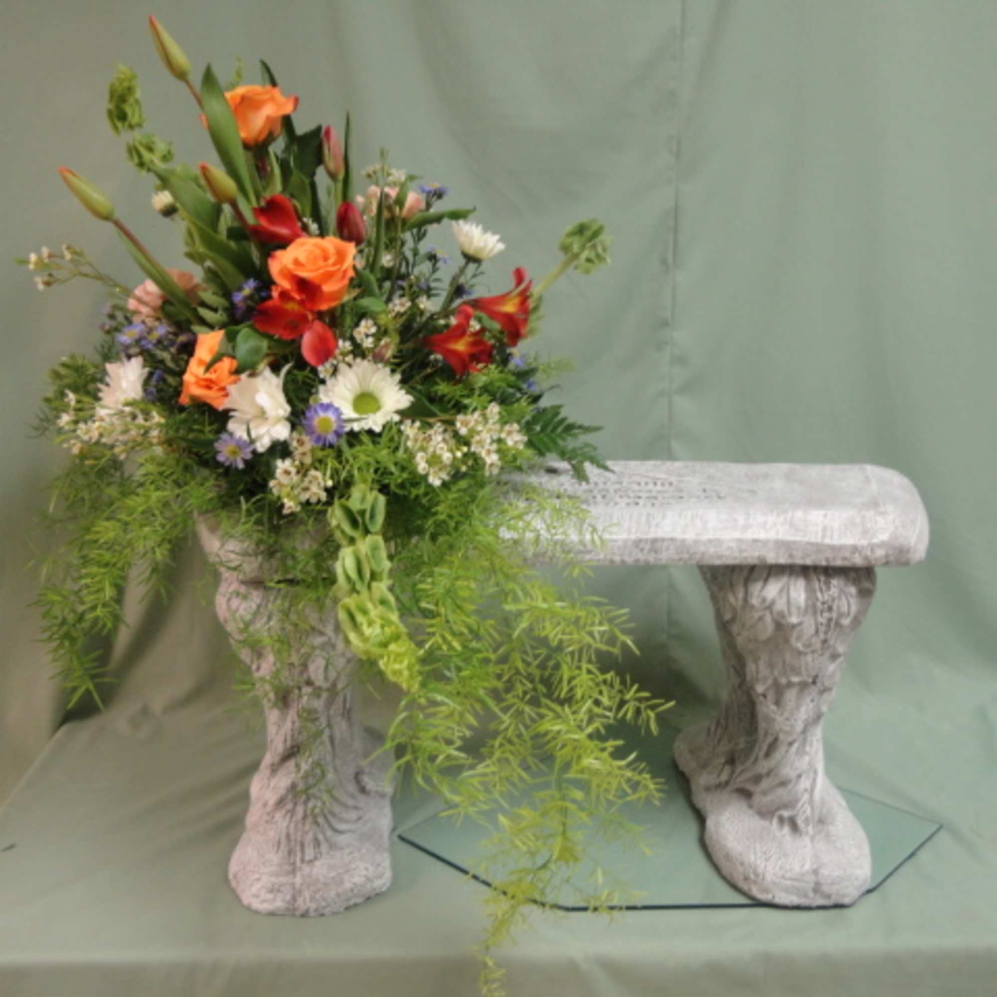 Colorful flower arrangement on a stone bench with trailing greenery