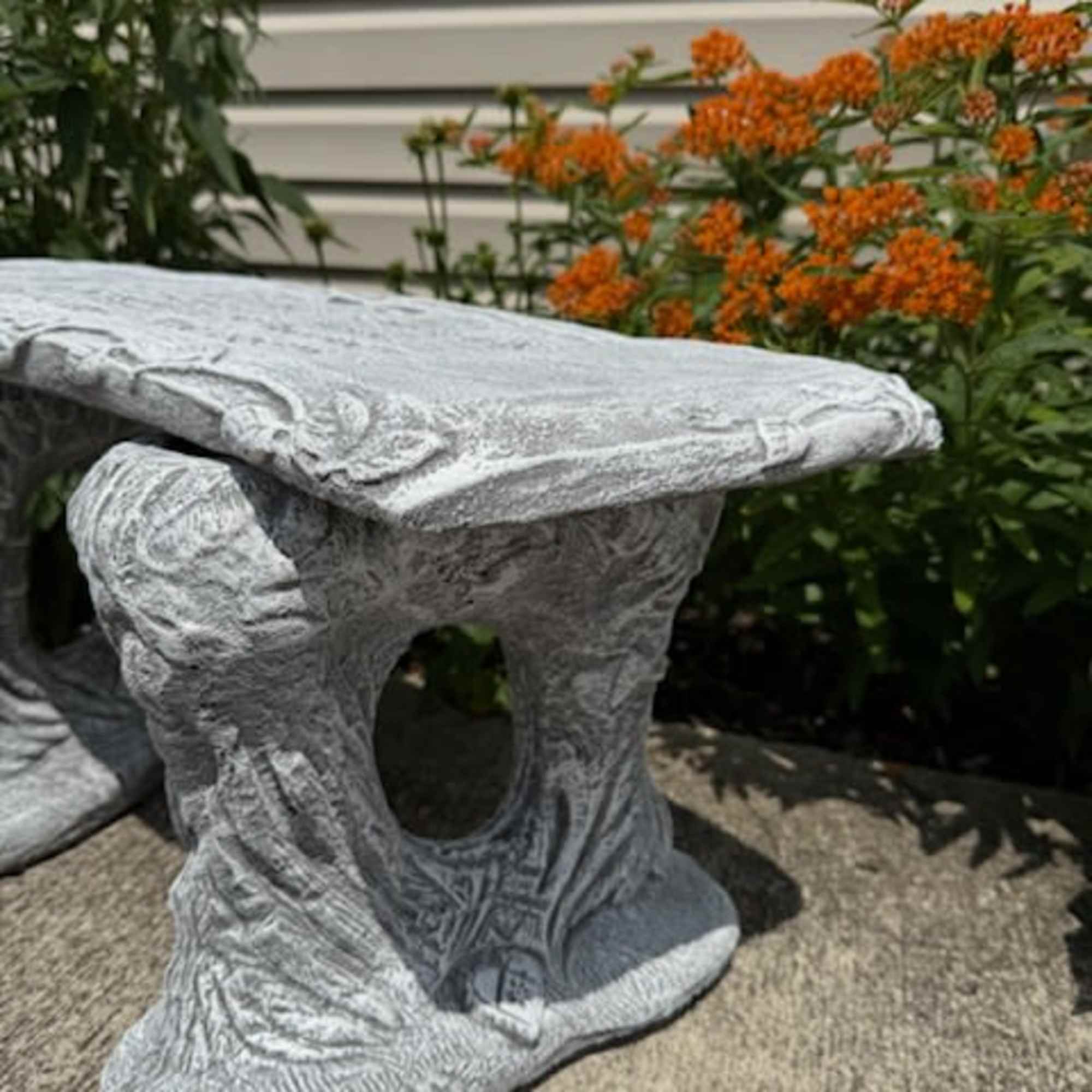 Stone garden bench beside orange flowers