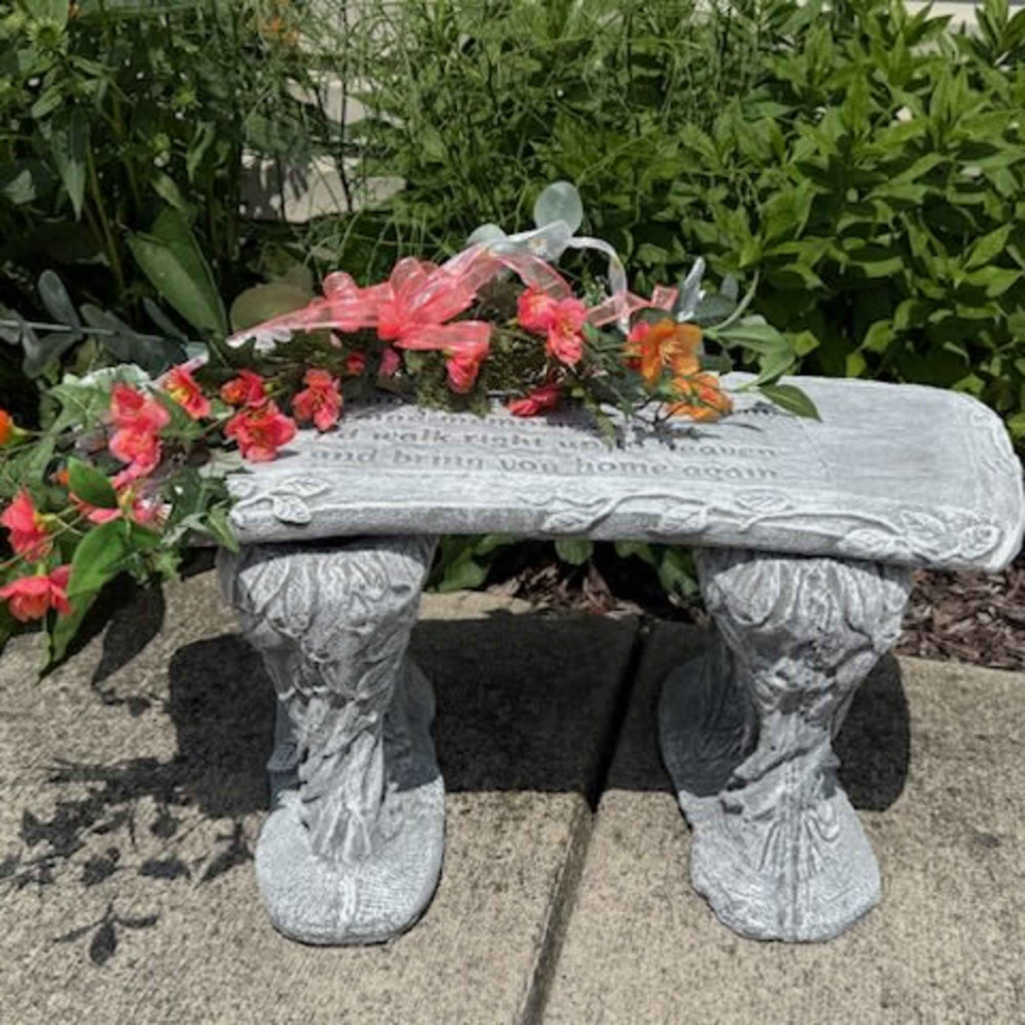 Floral arrangement draped over a stone bench with pink and orange blooms