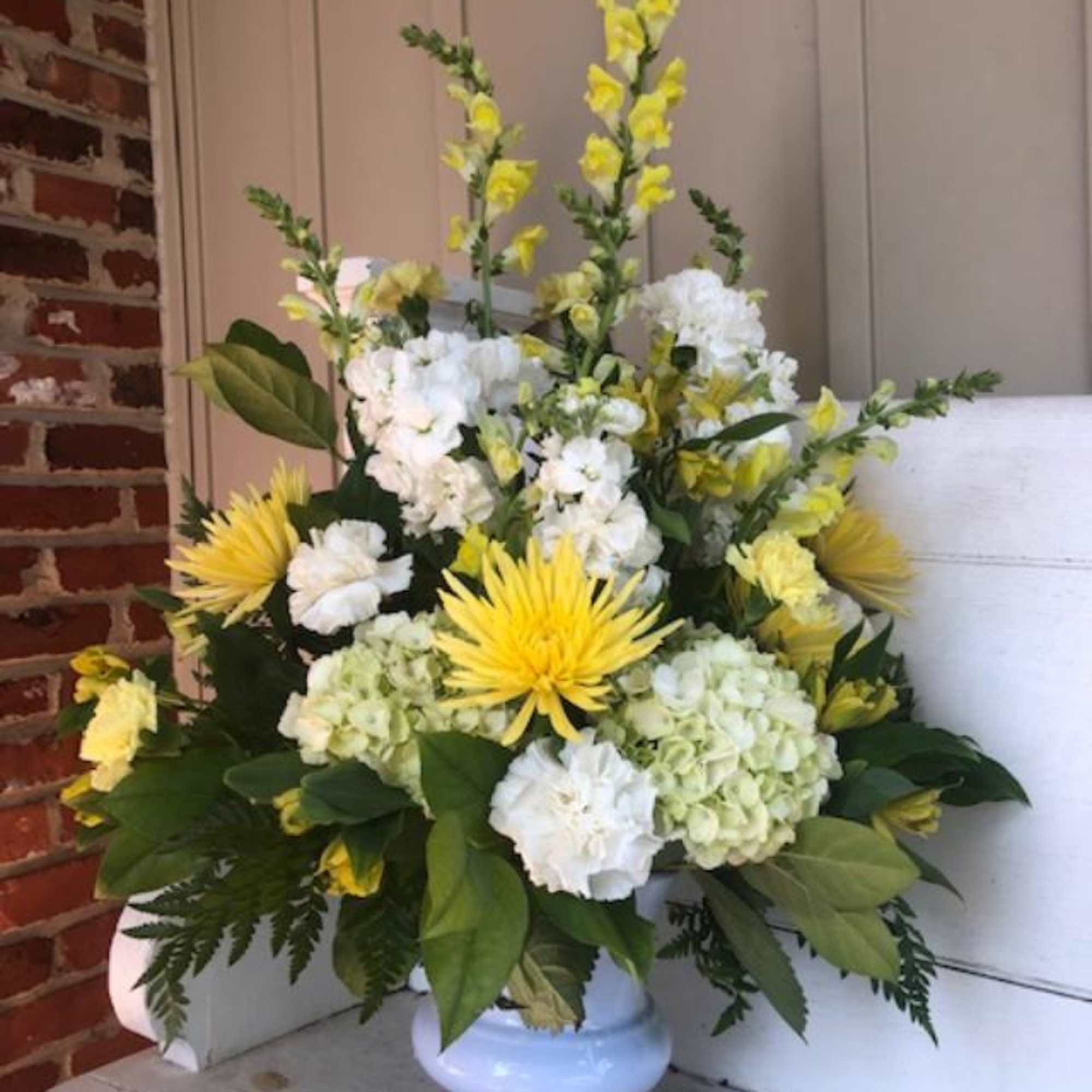 Yellow and white floral arrangement in a light blue vase