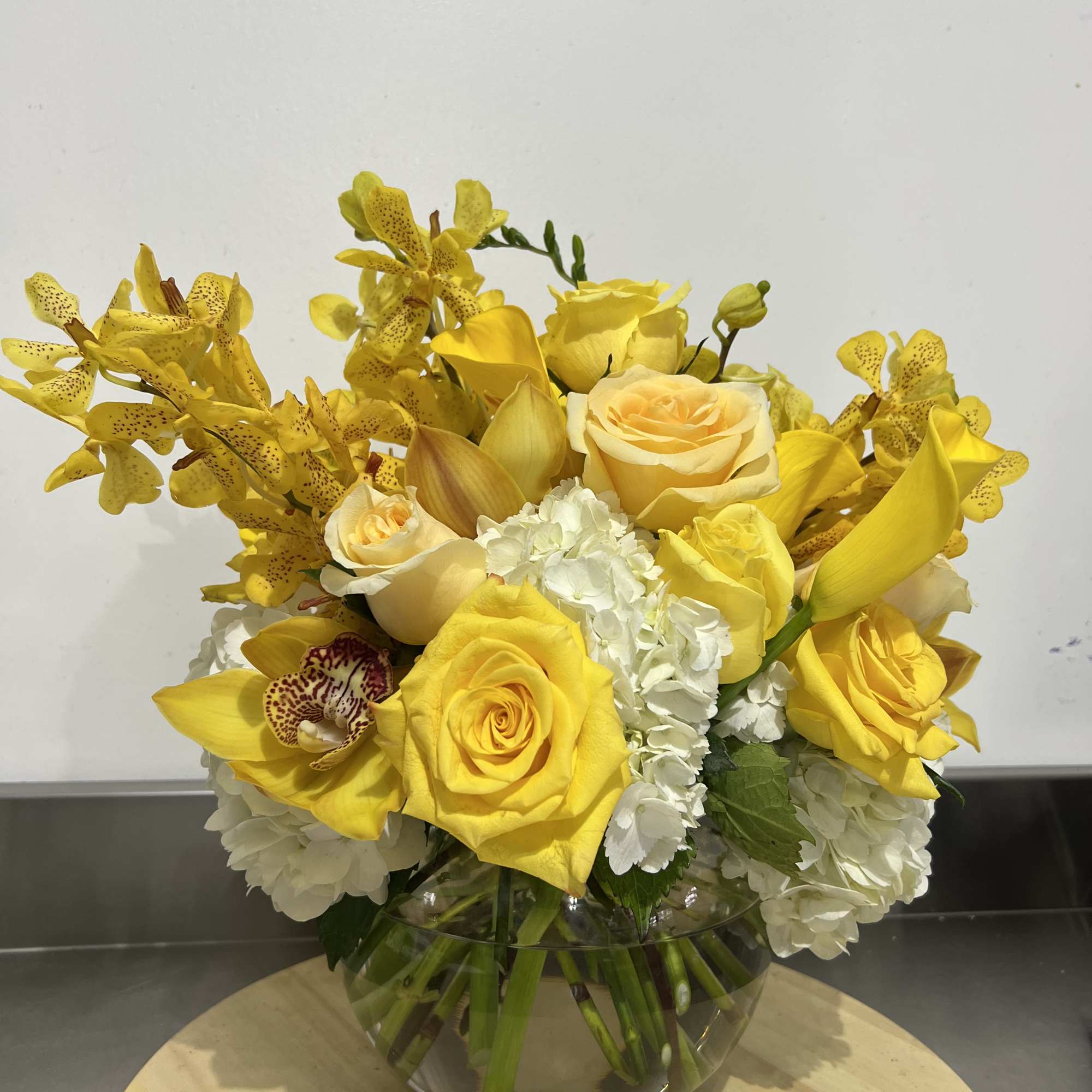 A bubble bowl fillies with gorgeous yellow blooms, mini calla lily, roses