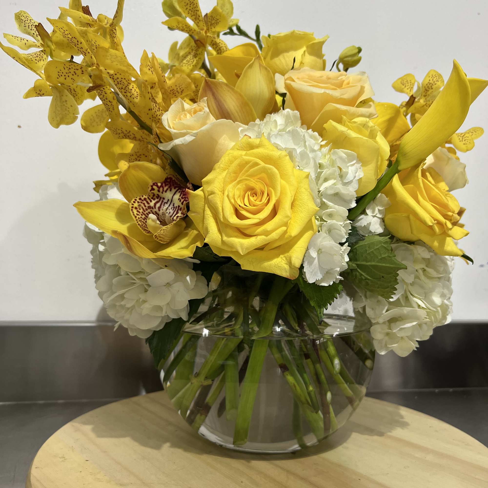 A bubble bowl fillies with gorgeous yellow blooms, mini calla lily, roses