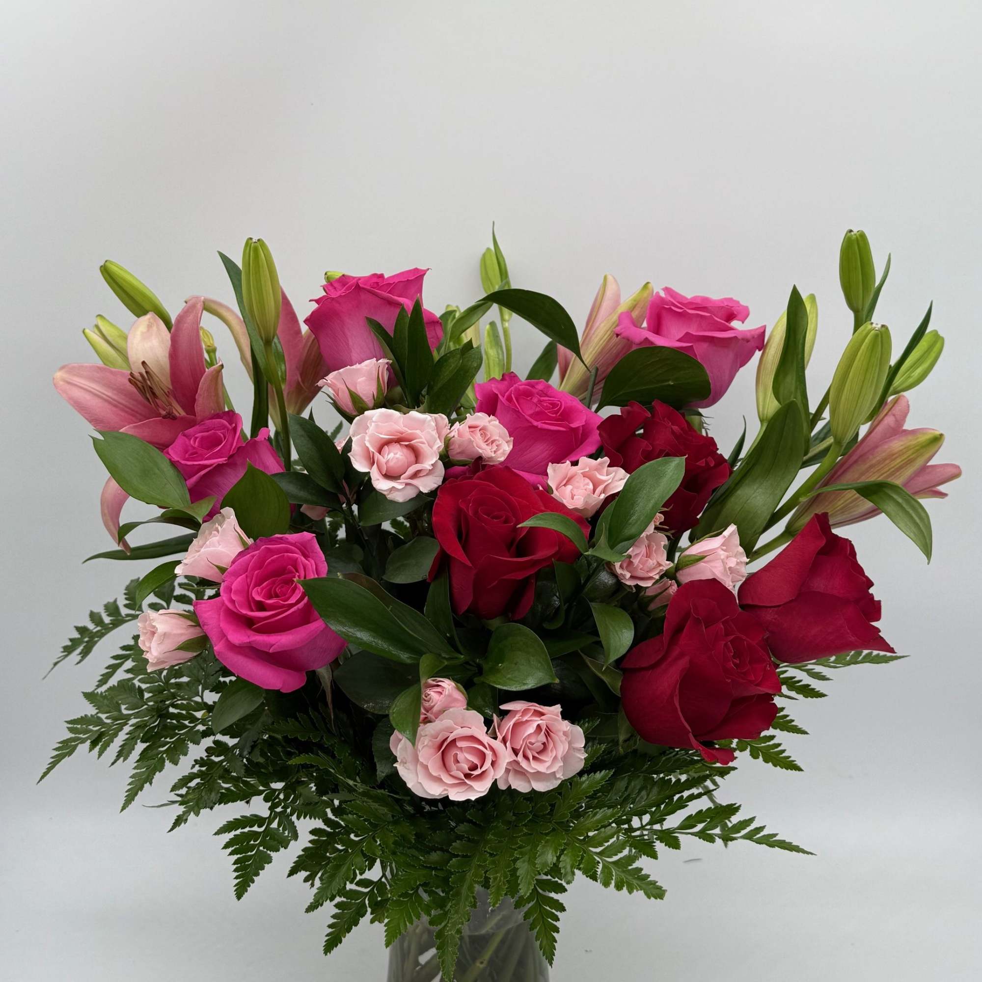 Pink and red roses with lilies in a glass vase