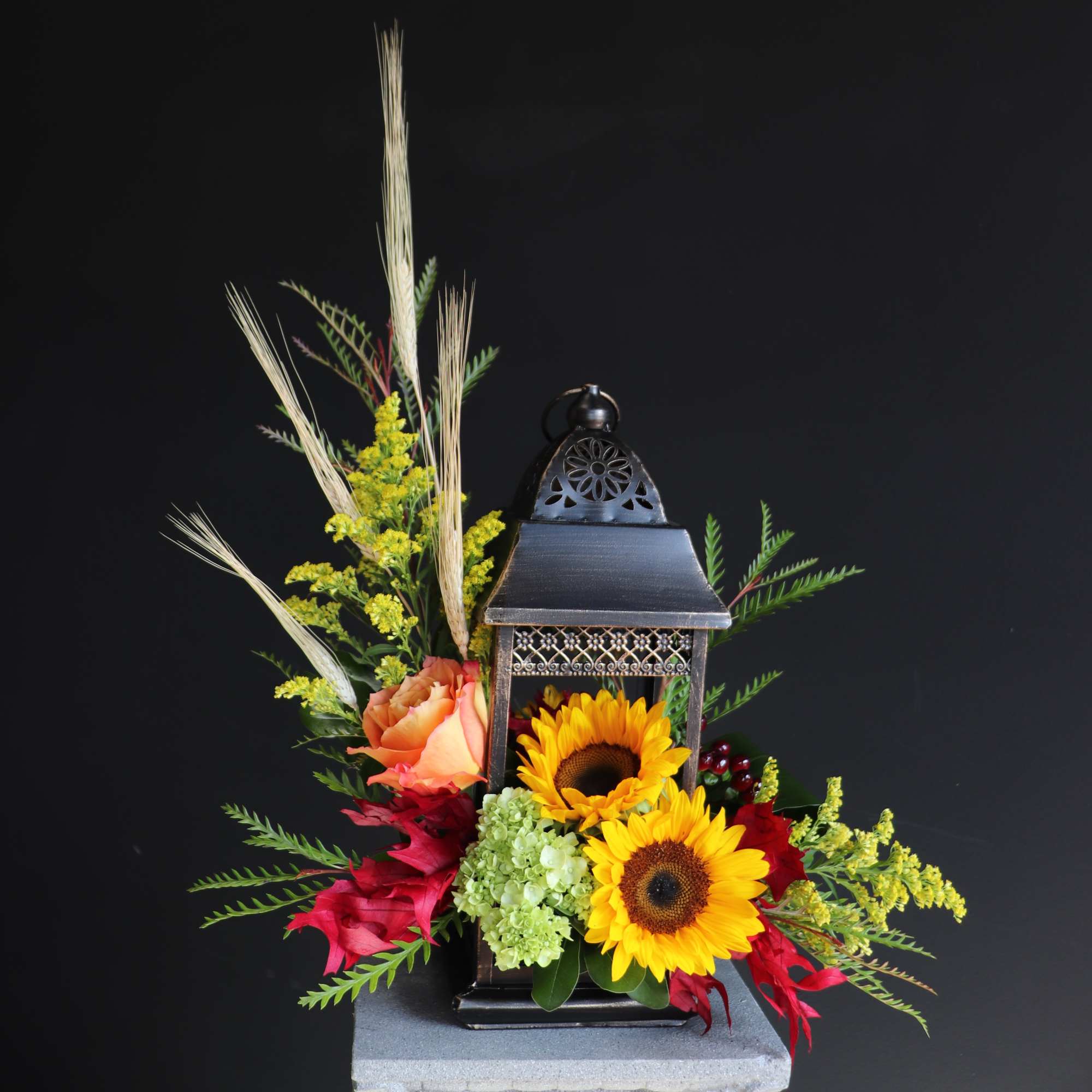 Lantern centerpiece with sunflowers, roses, and red flowers