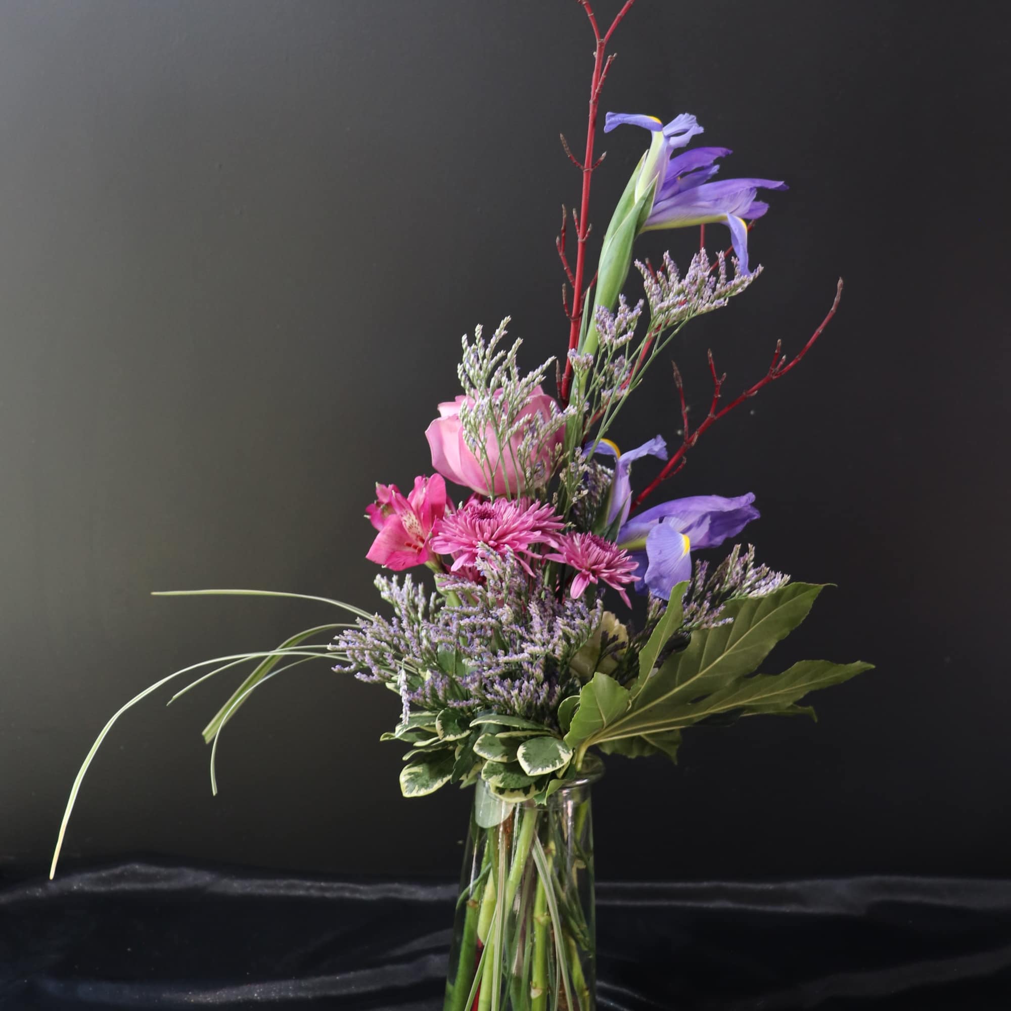 Tall mixed bouquet in a clear glass vase with purple and pink flowers