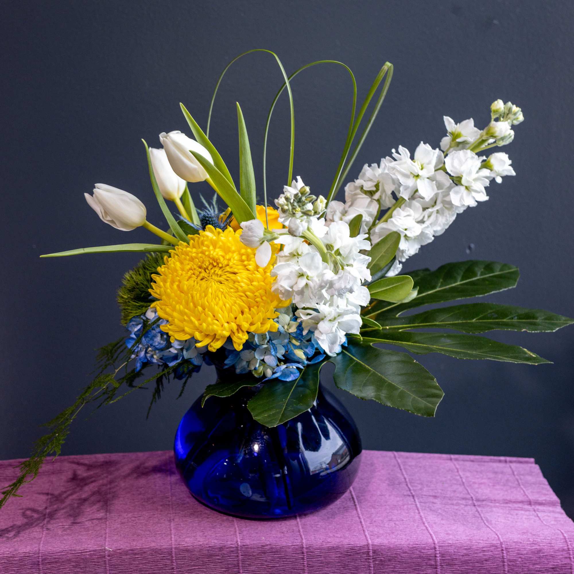 Yellow chrysanthemum and white tulips in a blue glass vase