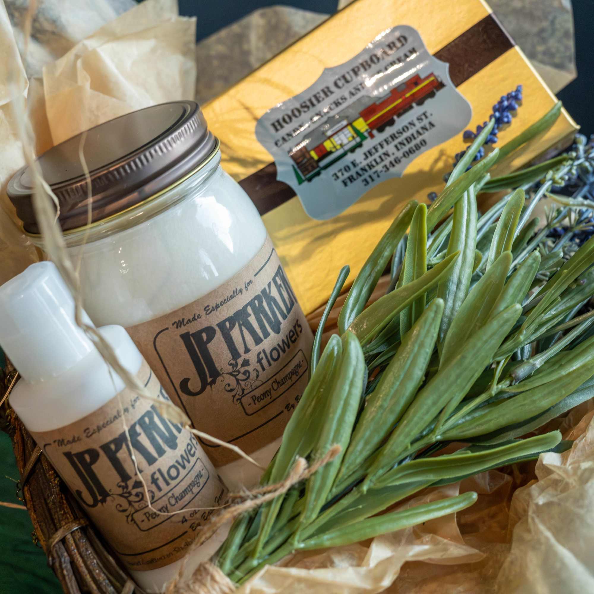 Gift basket with a candle, lotion, soap, and a wrapped floral bundle