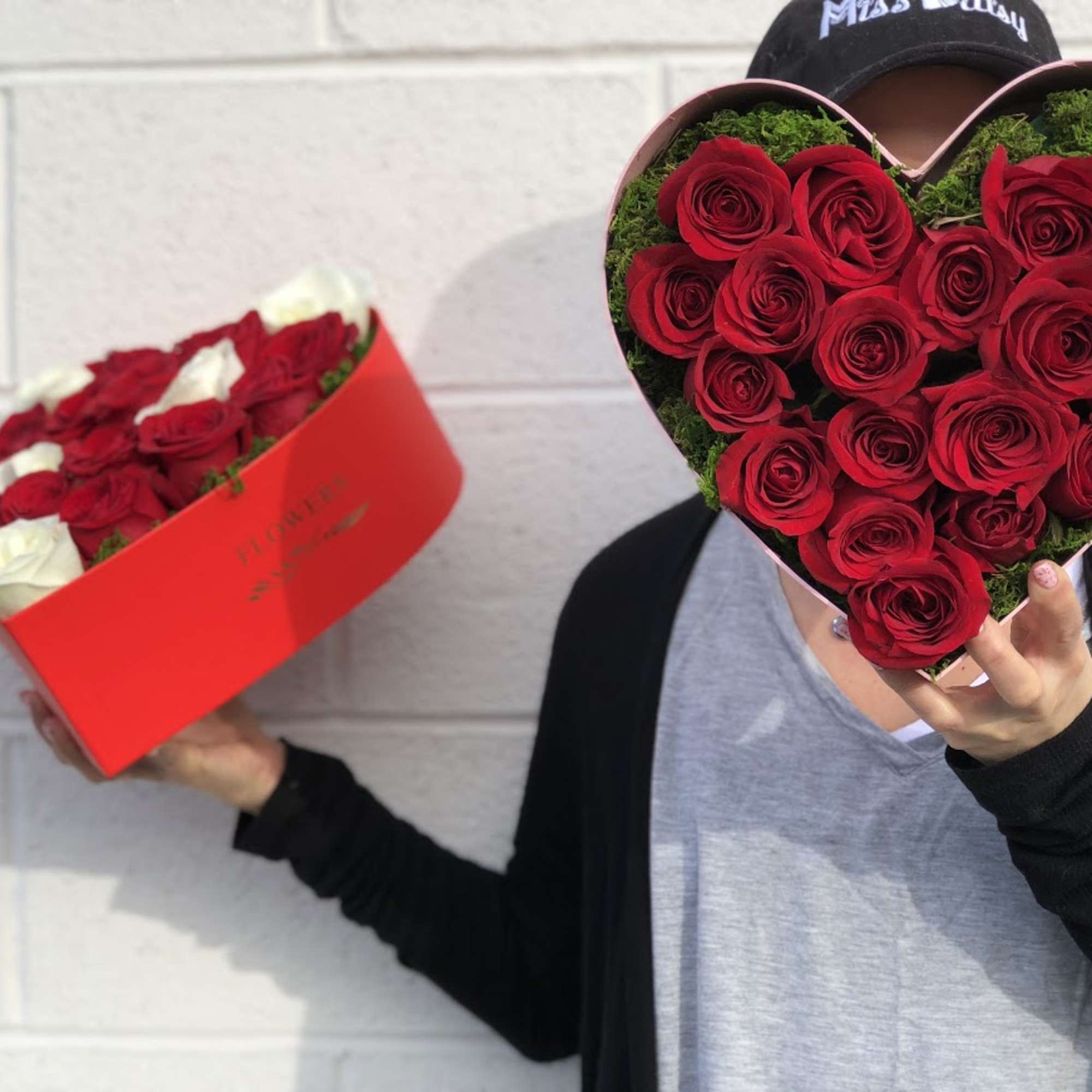 Heart-shaped box of red roses held beside a red rose box