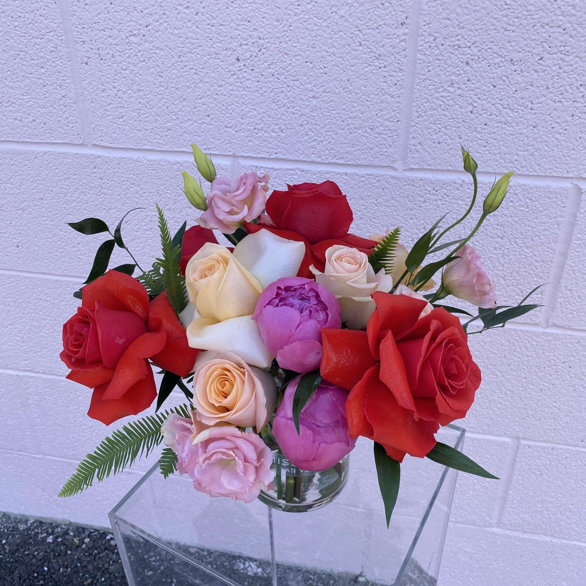 Bouquet of red, pink, and cream roses in a clear glass vase