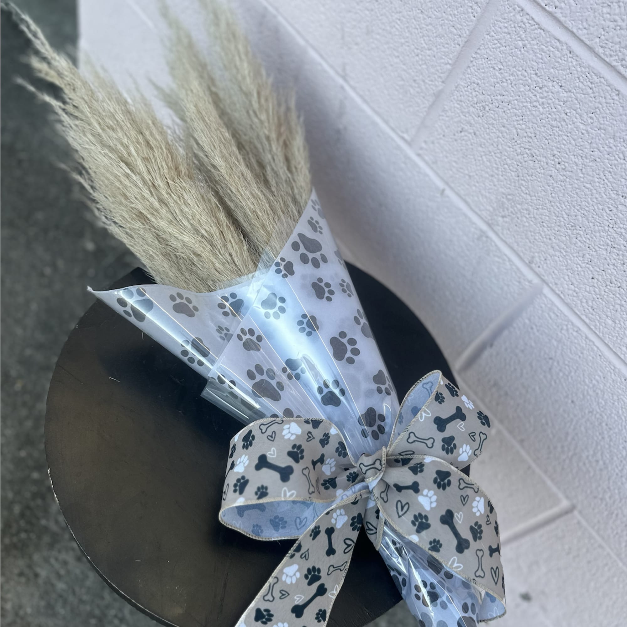 Bundle of dried pampas grass wrapped in paw-print cellophane with a bow