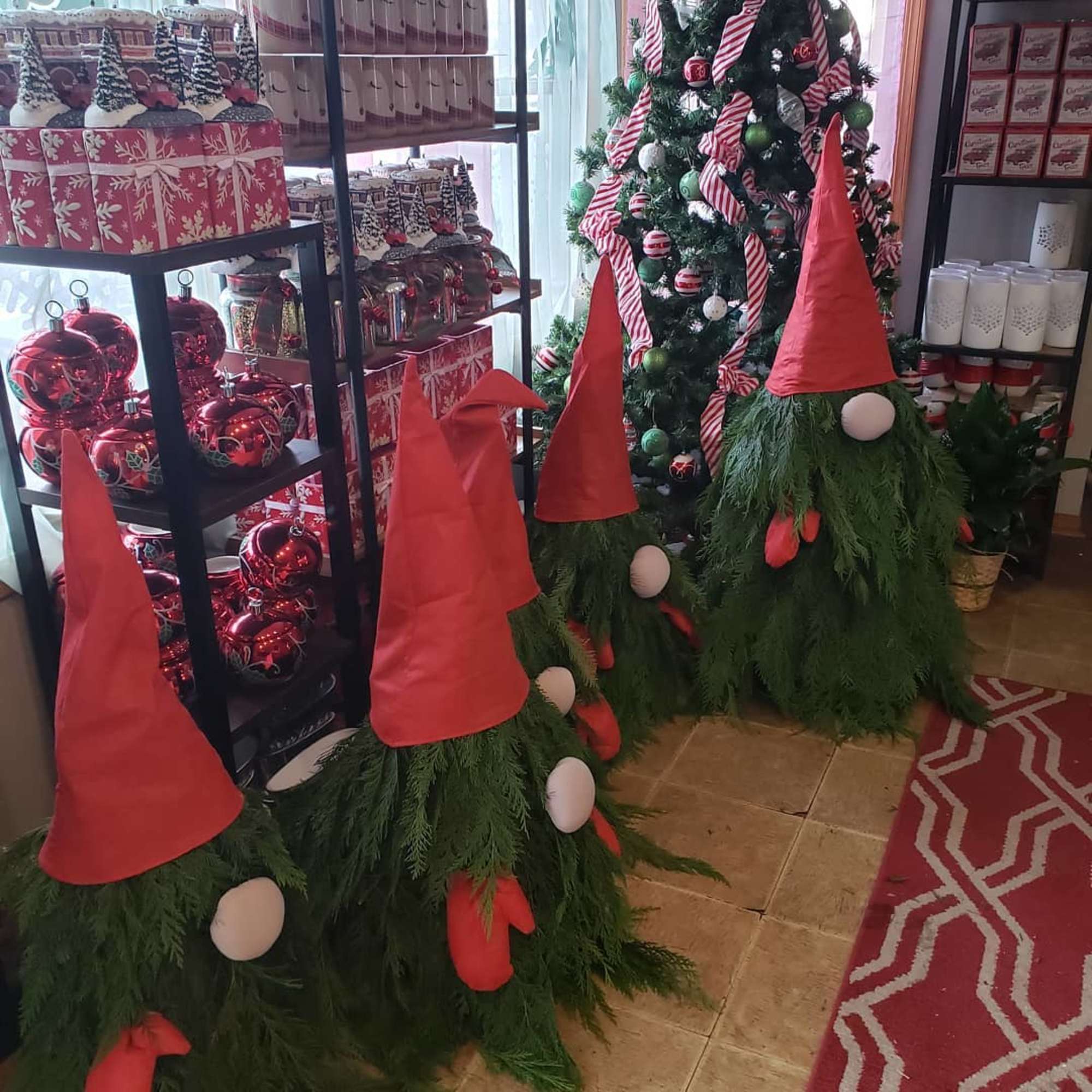 Christmas gnome decorations with red hats and greenery beside a decorated tree