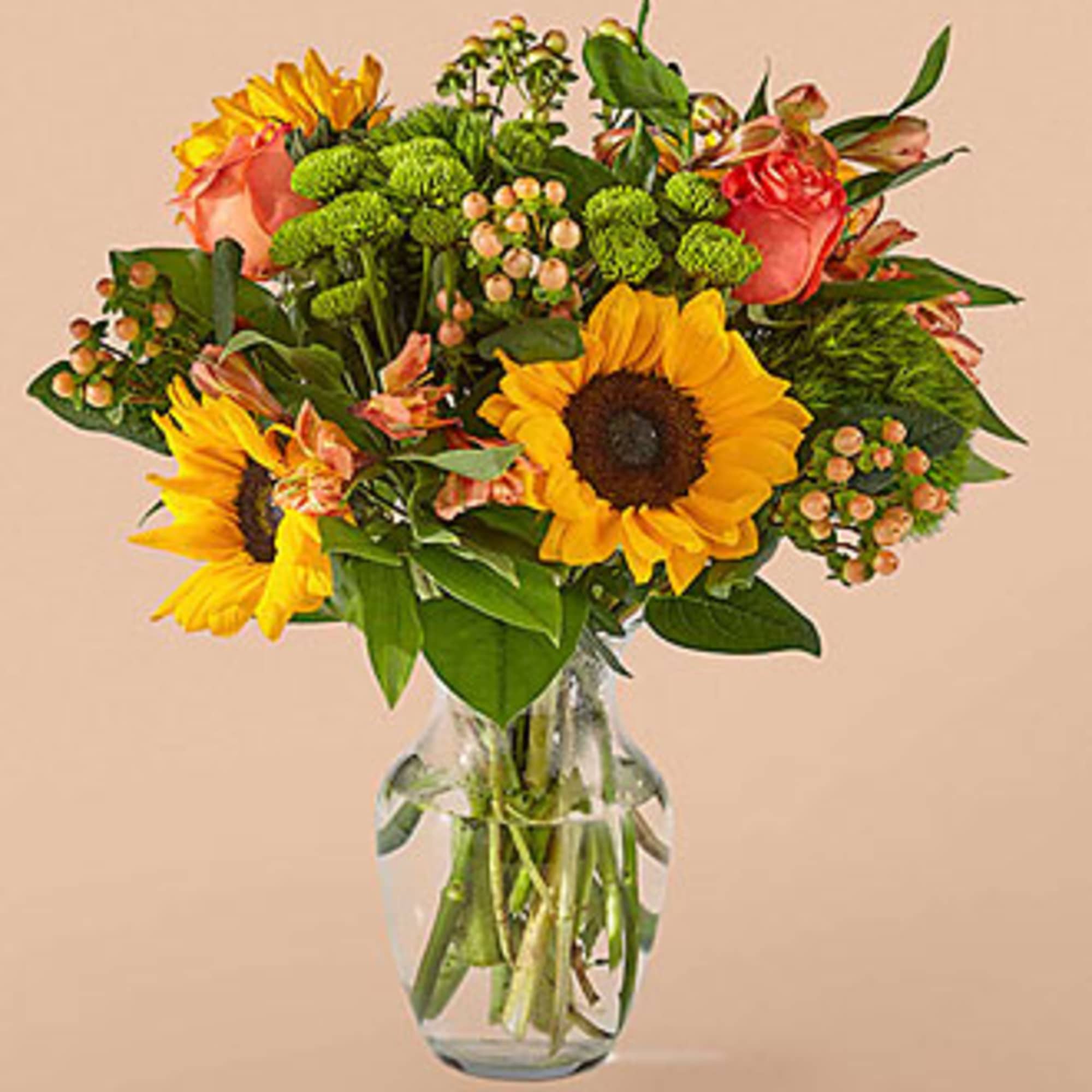 Sunflowers and roses arranged in a clear glass vase