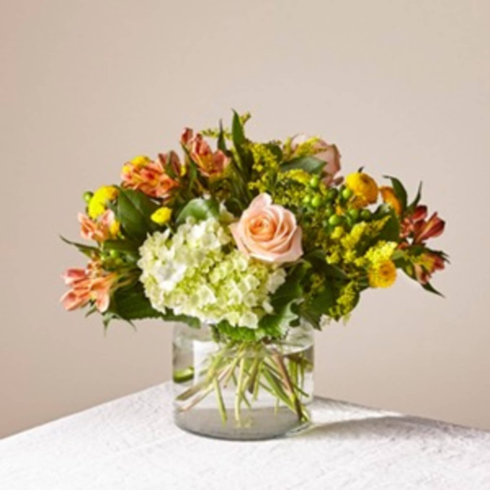 Mixed bouquet with a peach rose and white hydrangea in a glass vase