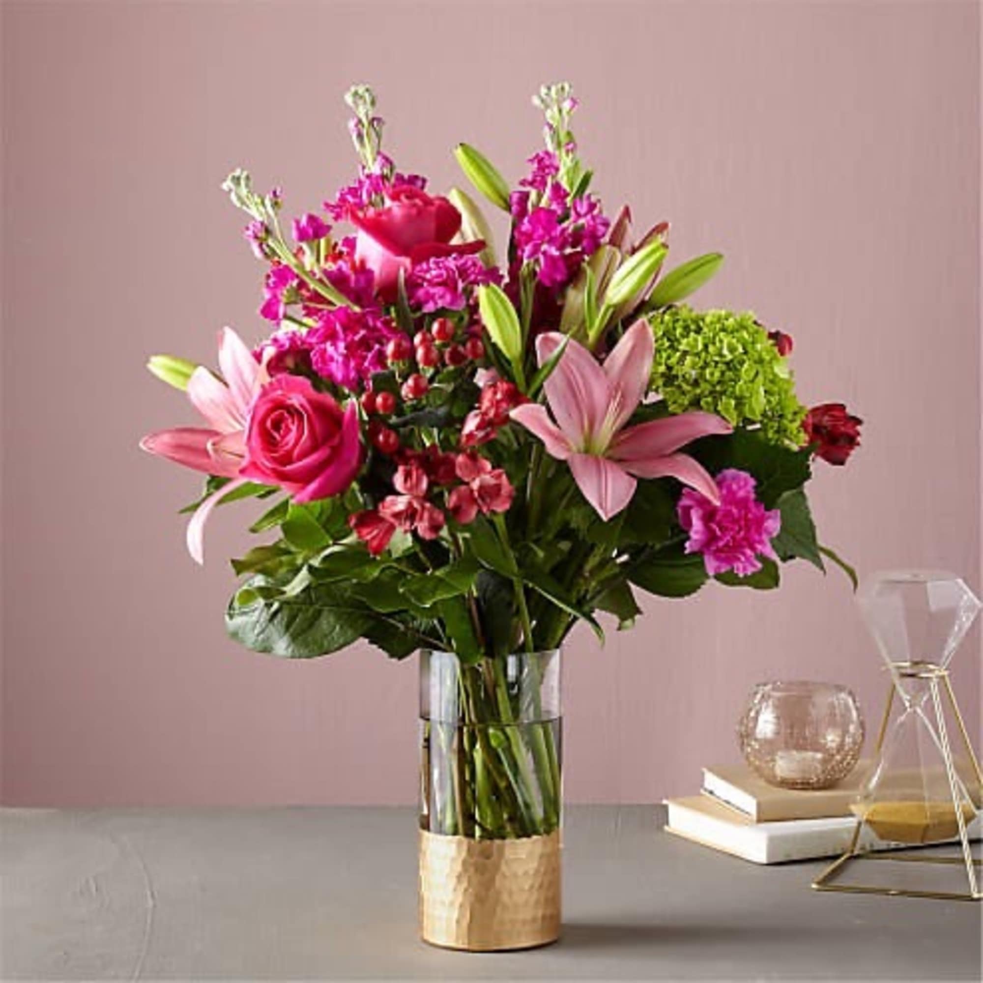 Pink and magenta bouquet with lilies and roses in a glass vase