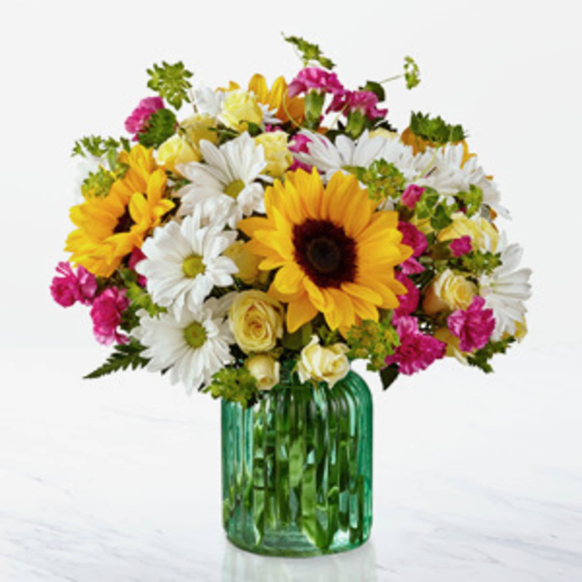 Bouquet of sunflowers, white daisies, and pink flowers in a green glass vase