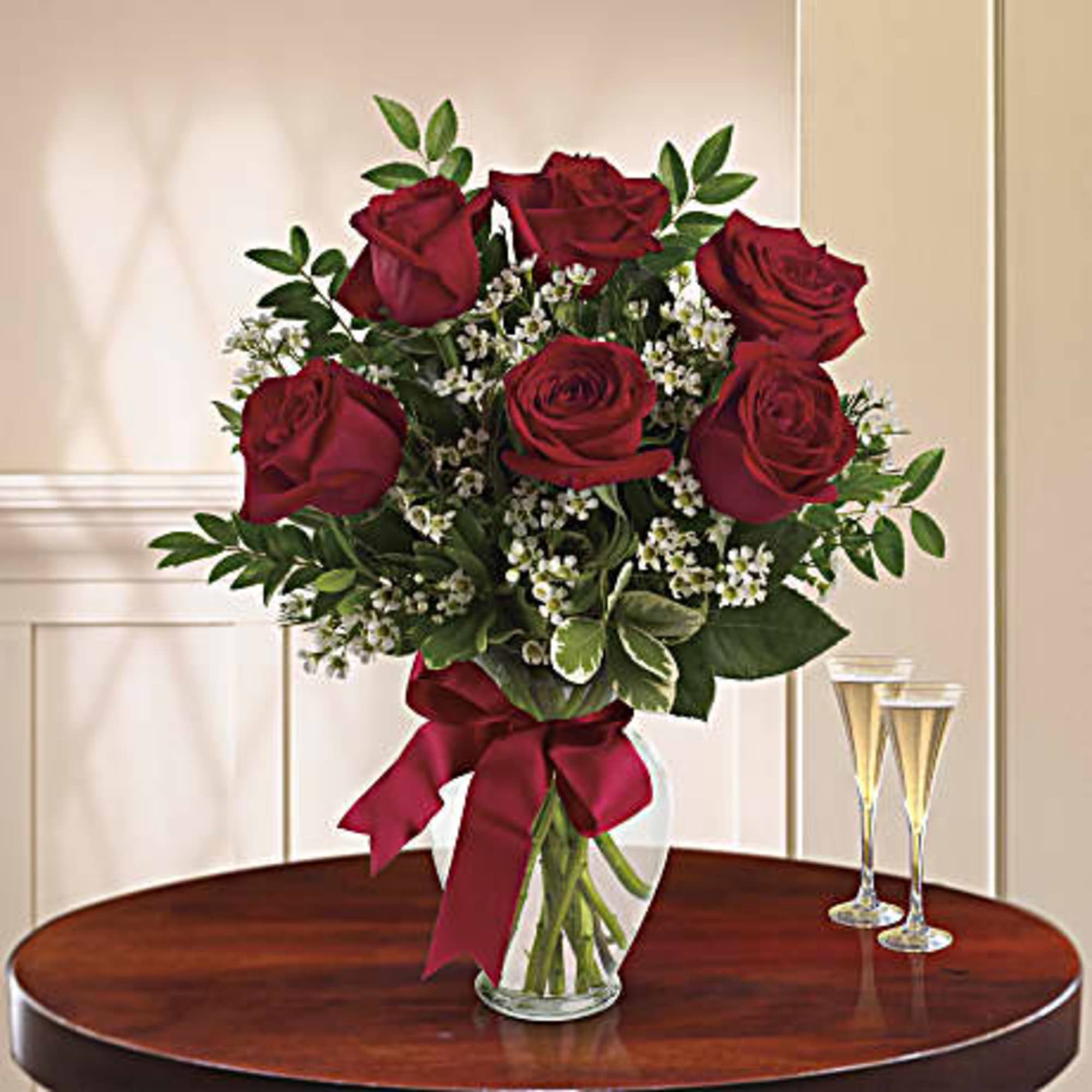Bouquet of red roses in a glass vase with a burgundy ribbon