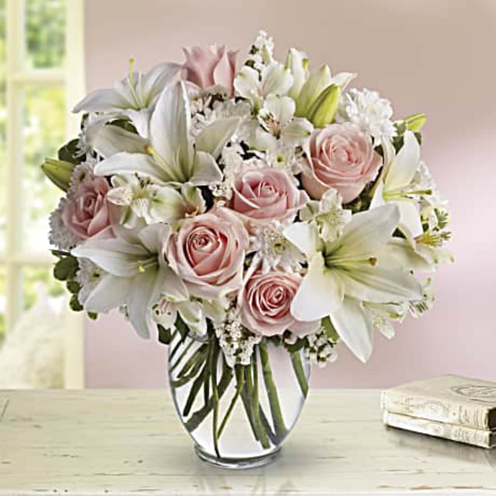 Pink roses and white lilies arranged in a clear glass vase