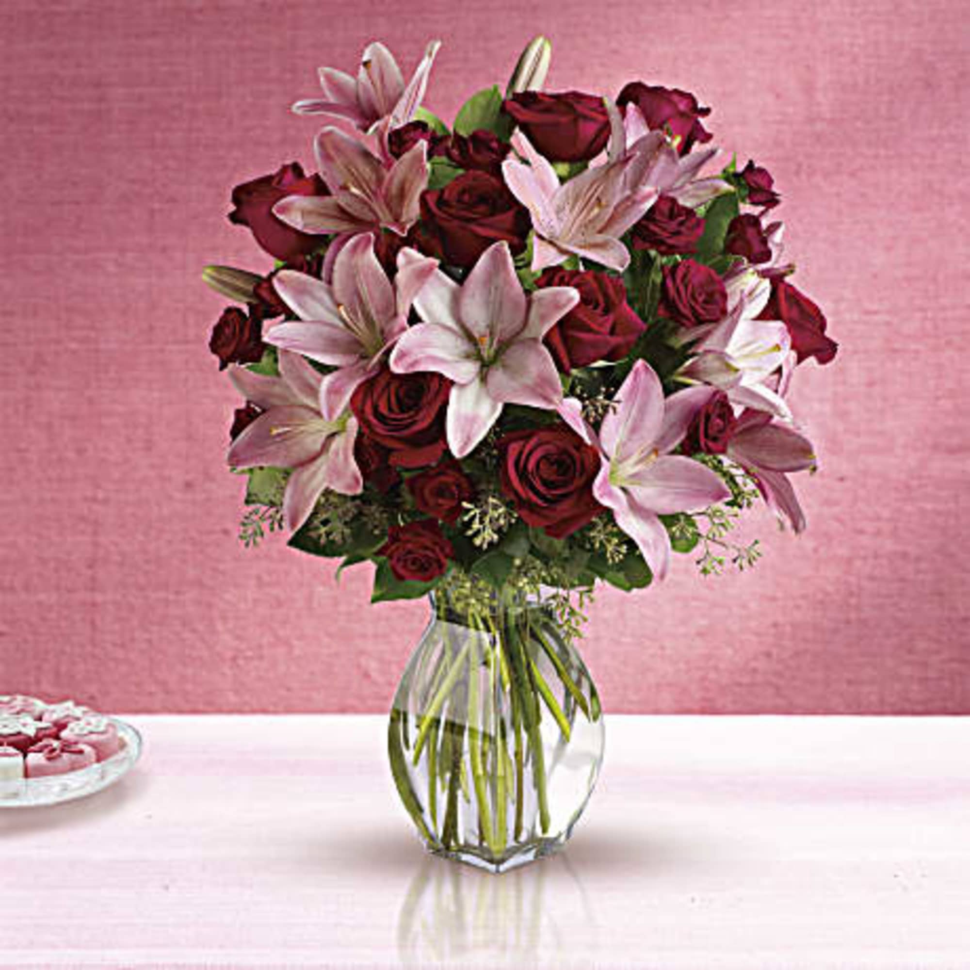 Bouquet of red roses and pink lilies in a clear glass vase