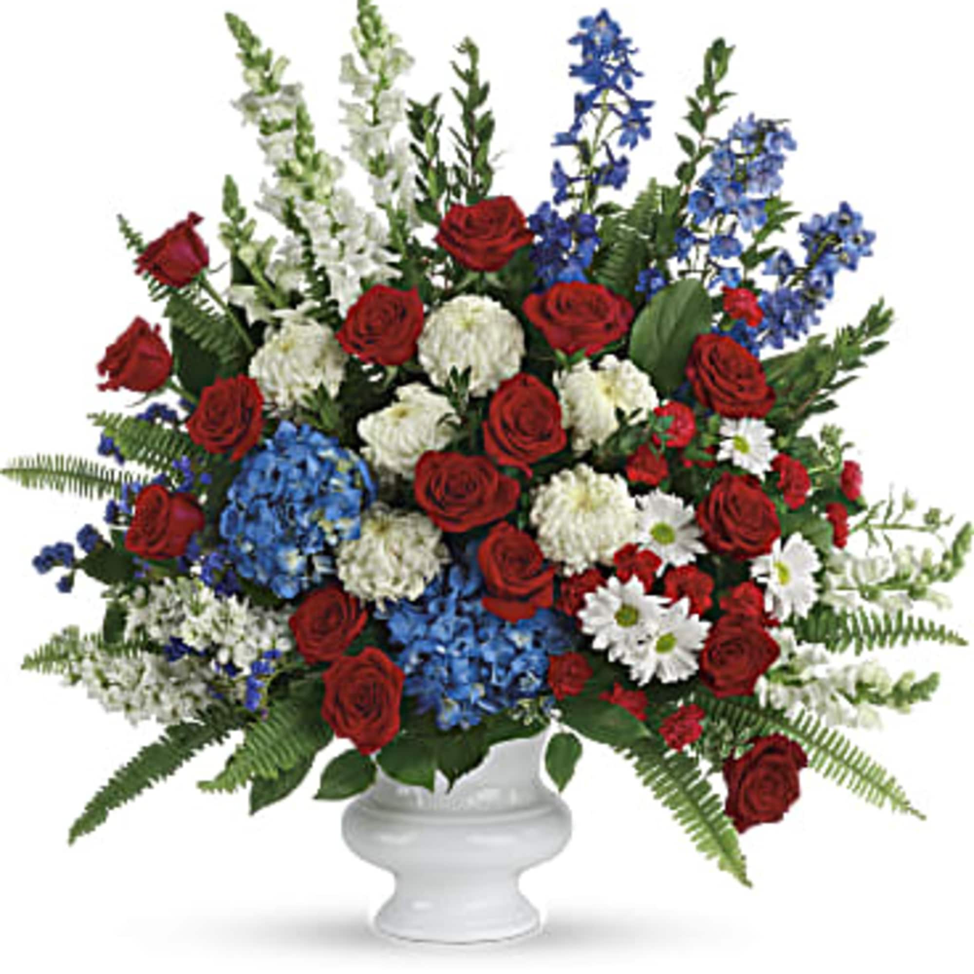 Red roses, blue flowers, and white blooms in a white urn vase