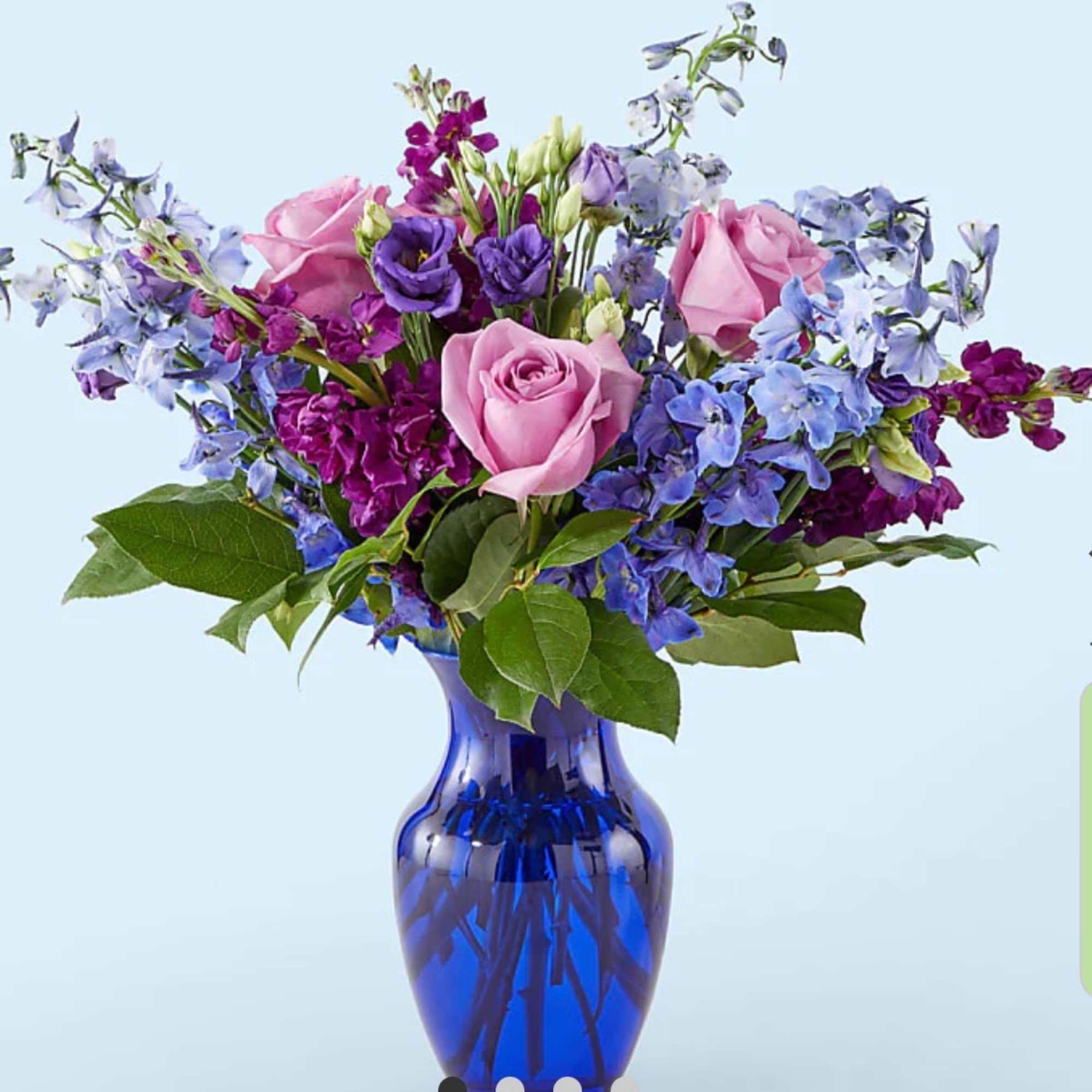 Pink roses and purple flowers in a blue glass vase