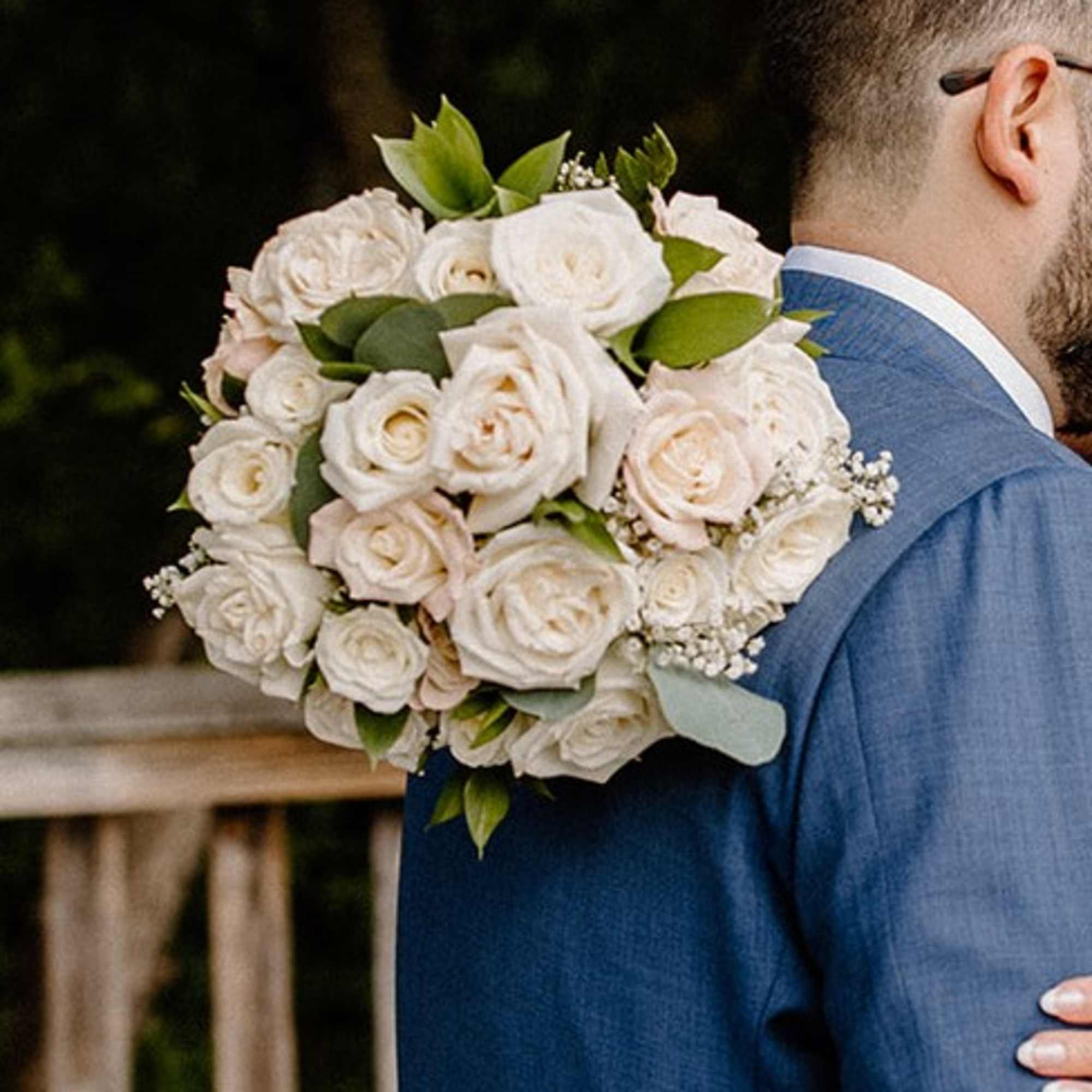 White rose bouquet held against a blue suit