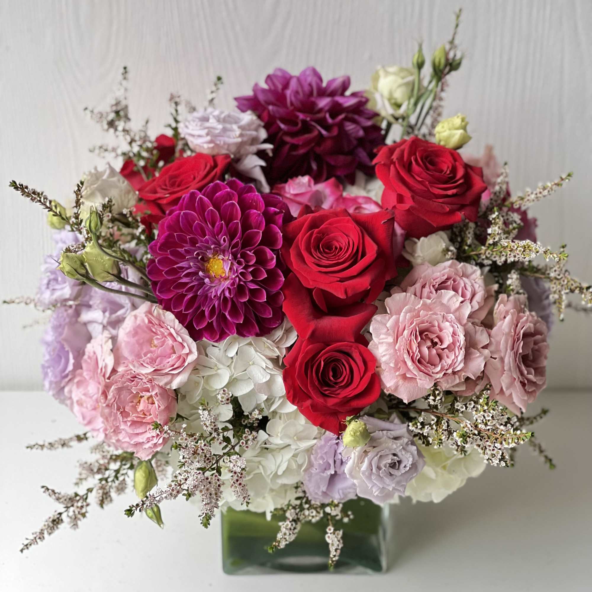 Bouquet of red and pink roses with dahlias in a glass vase