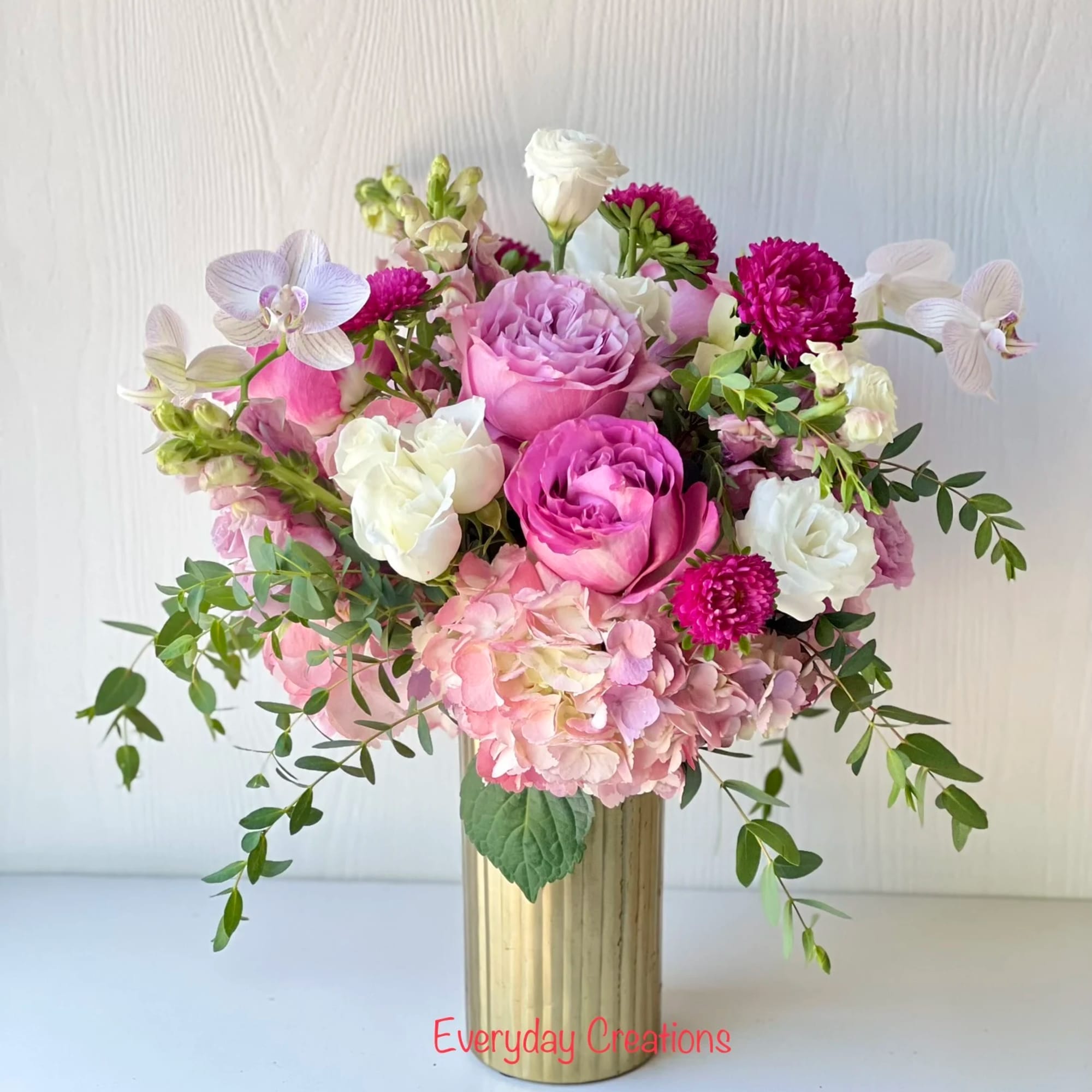 Pink and white floral arrangement in a gold vase