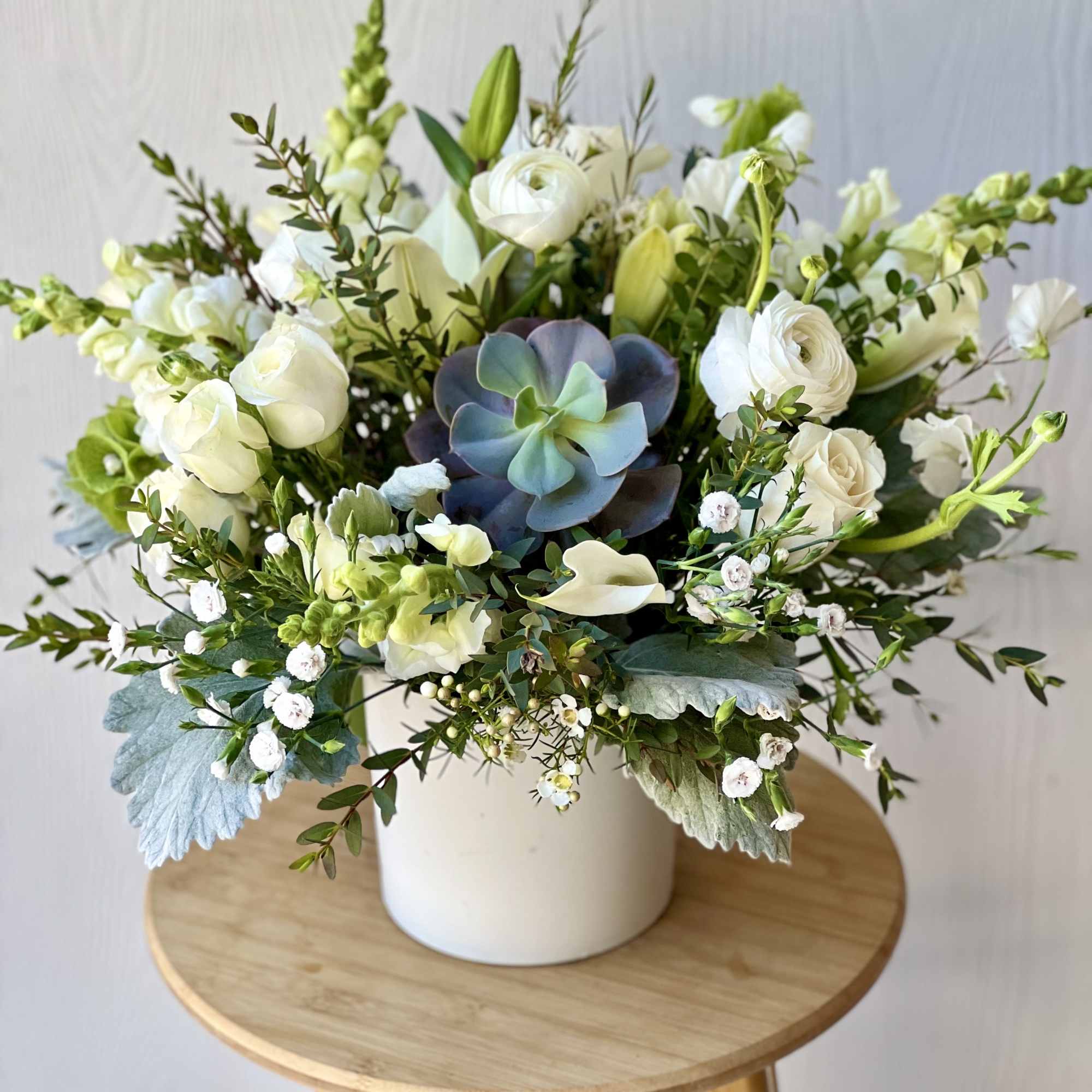 White floral arrangement with a succulent in a white vase