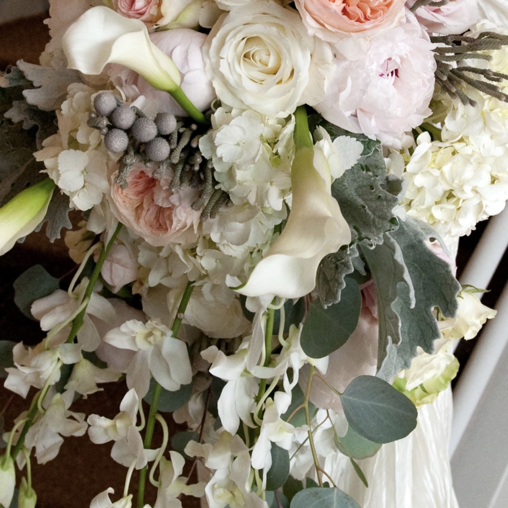 Hand-tied bouquet of pale pink and white flowers with trailing greenery
