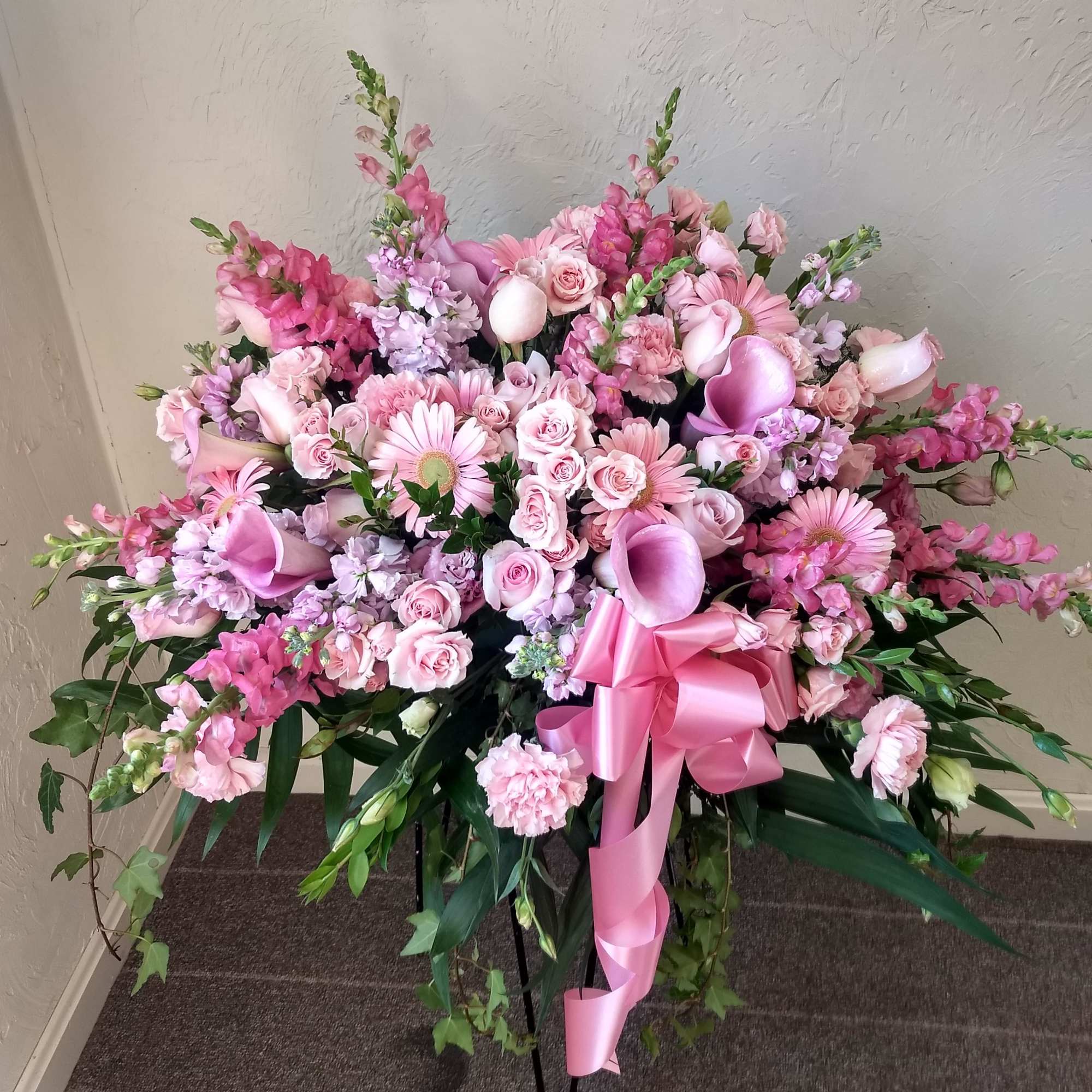 Large pink floral spray with roses, calla lilies, and a ribbon bow