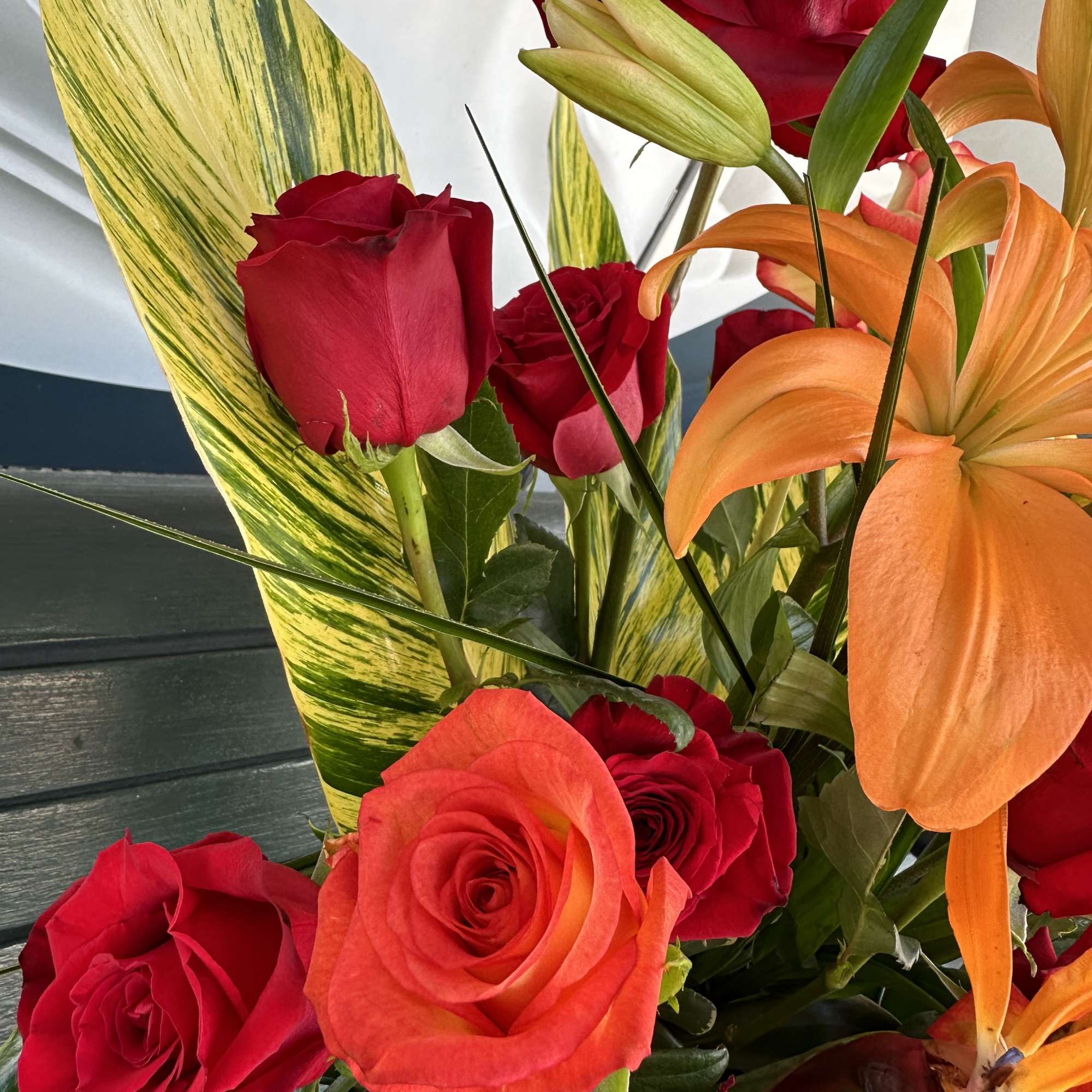 Bouquet of red roses and orange lilies with variegated leaves