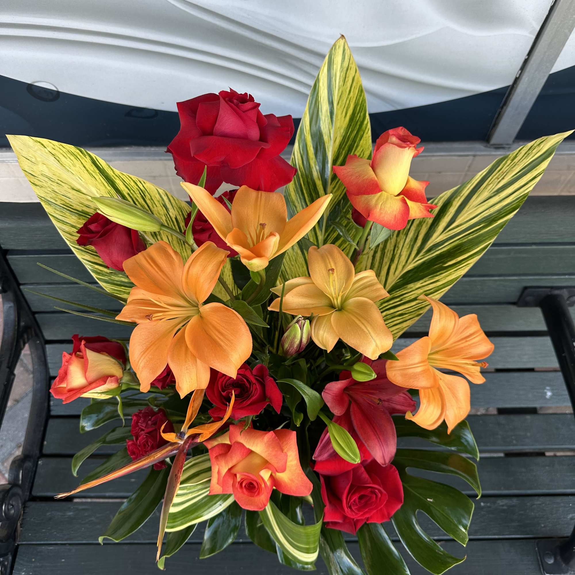 Bouquet of red roses and orange lilies with striped leaves