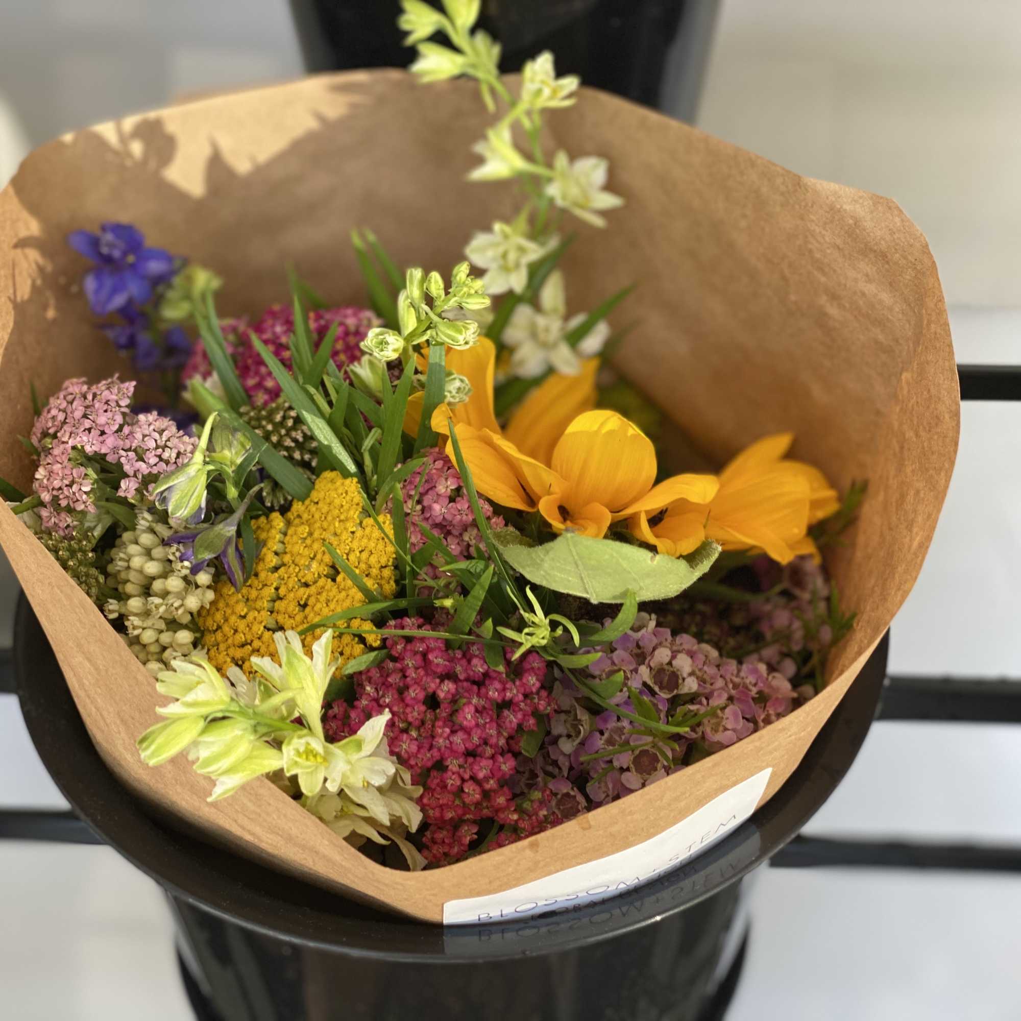 Mixed bouquet with yellow, pink, purple, and white flowers in brown paper