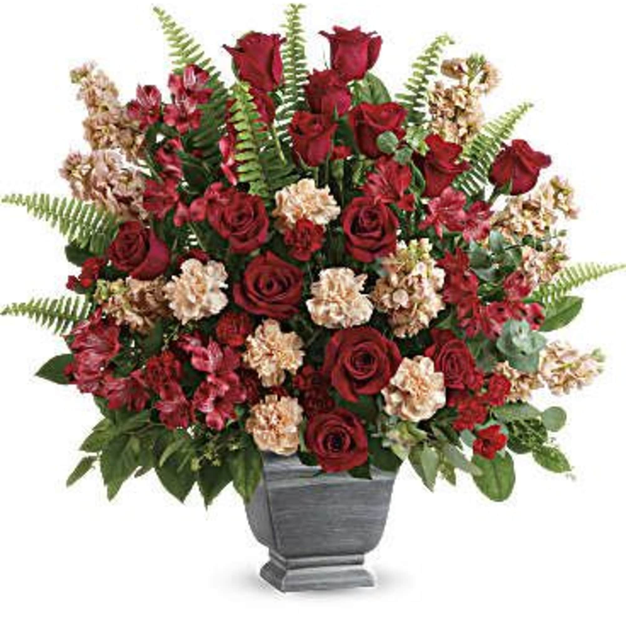 Red roses and pink carnations arranged in a gray urn vase