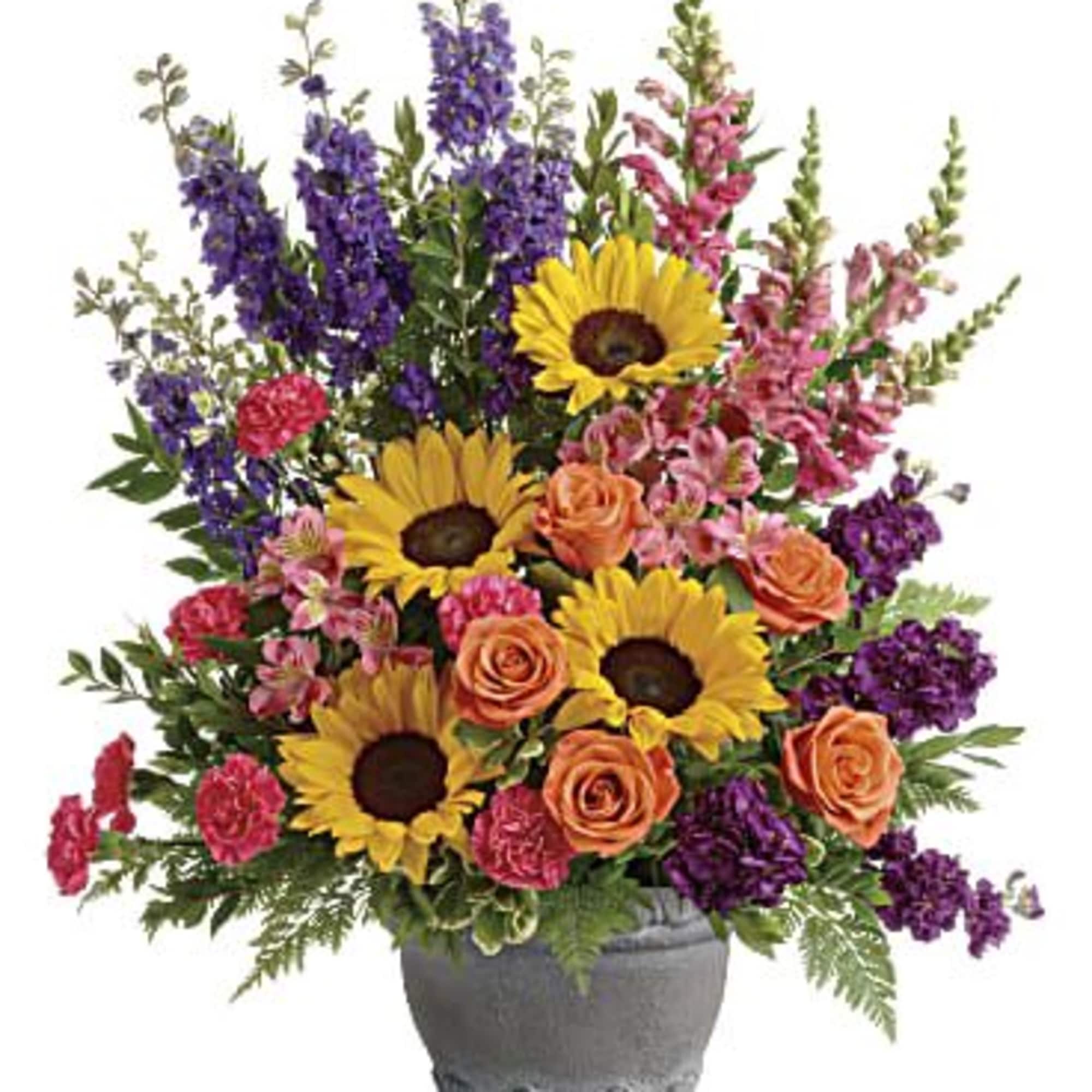 Mixed bouquet with sunflowers, roses, and purple spikes in a gray vase