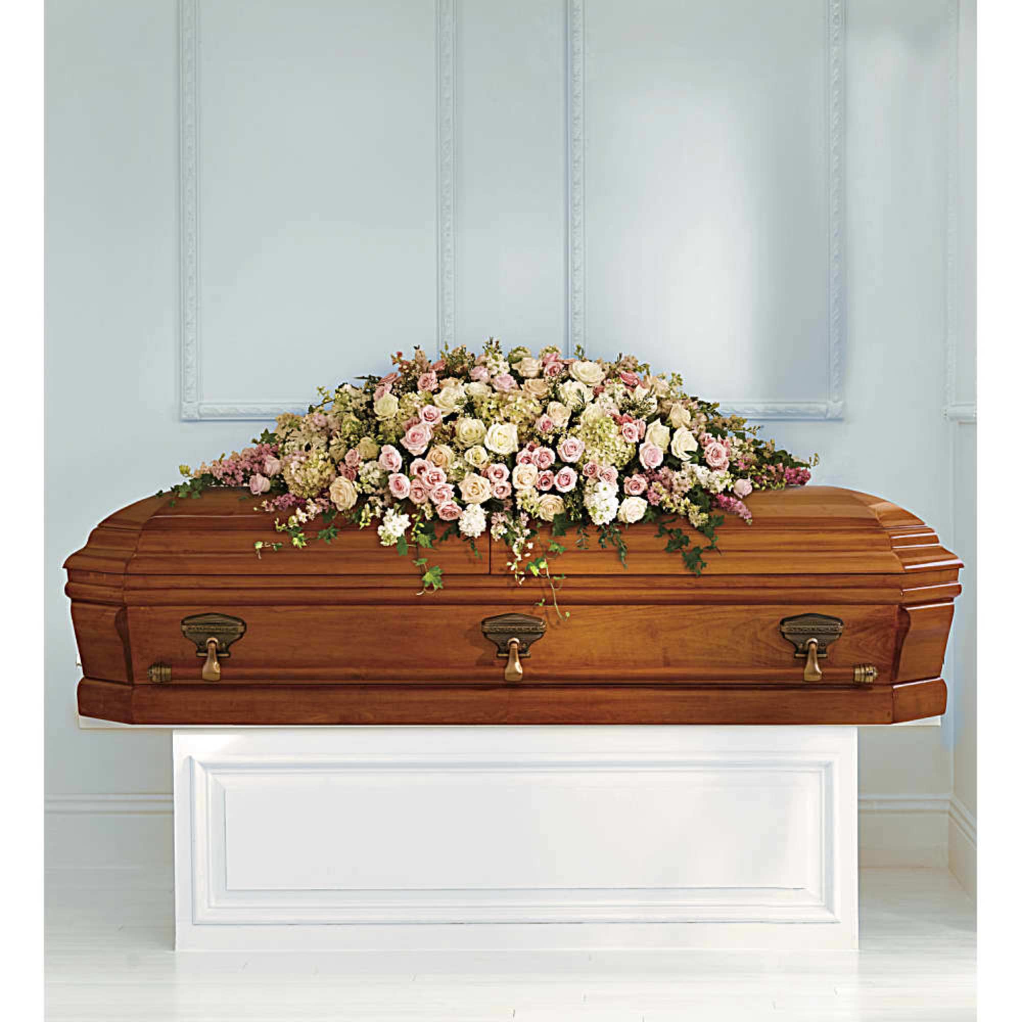 Casket topped with a pastel rose floral spray