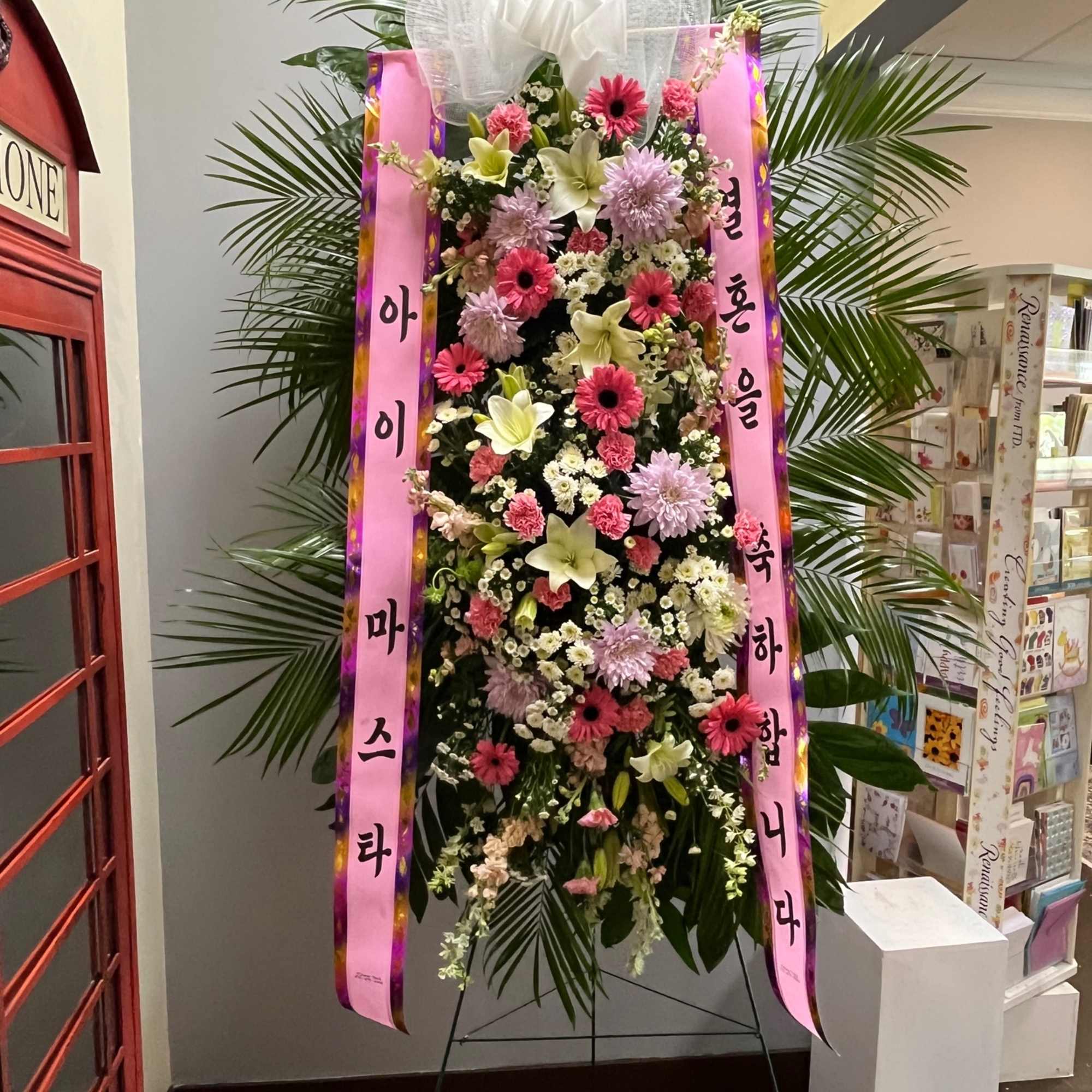 Tall standing floral spray with pink ribbons and a white bow