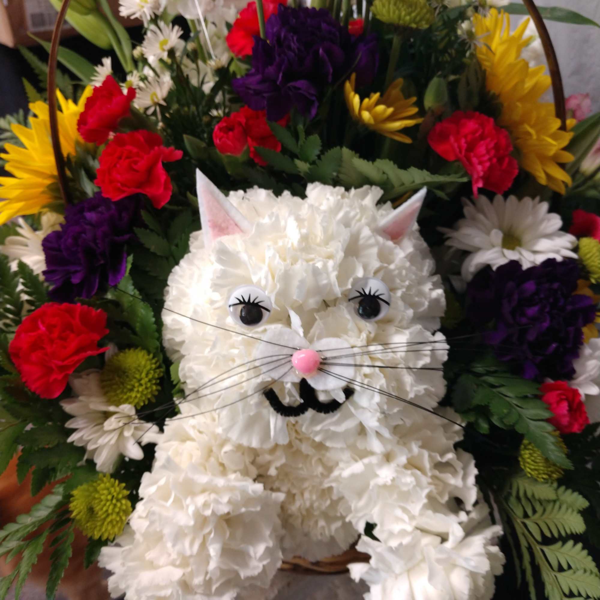 White floral cat figure surrounded by colorful flowers in a basket
