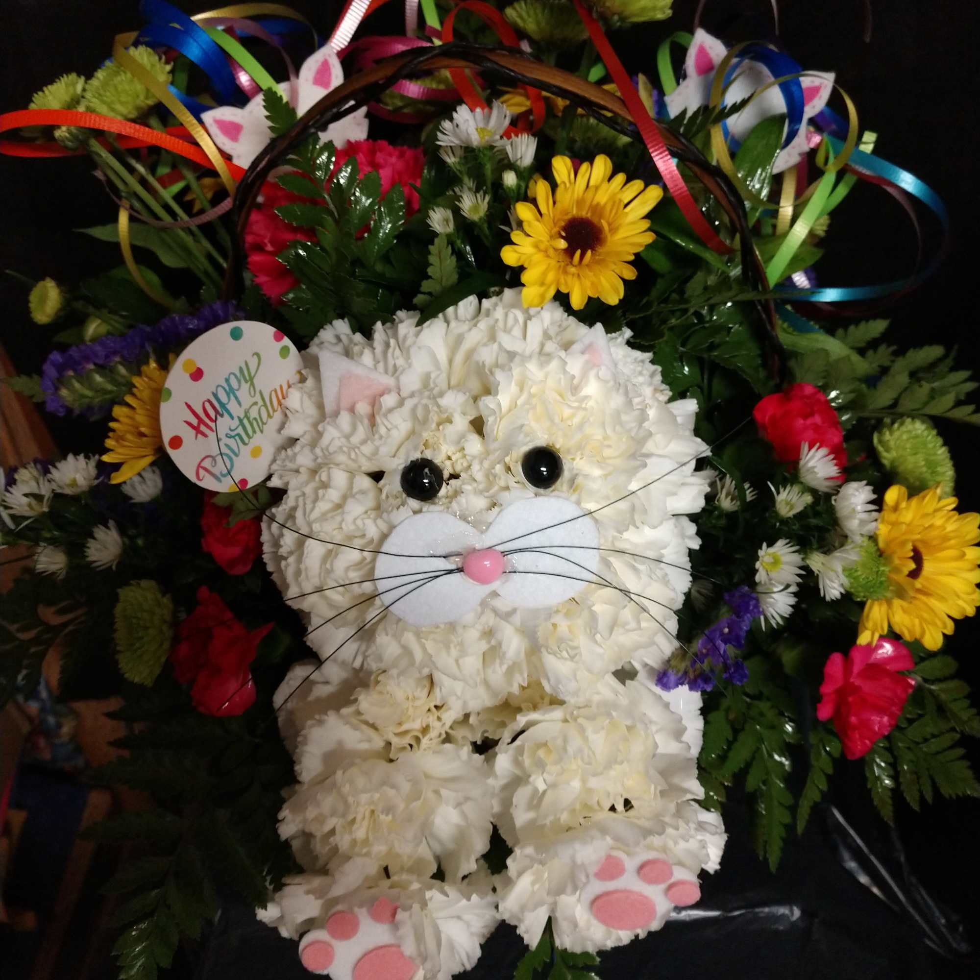 White flower cat arrangement with colorful ribbons and a birthday tag